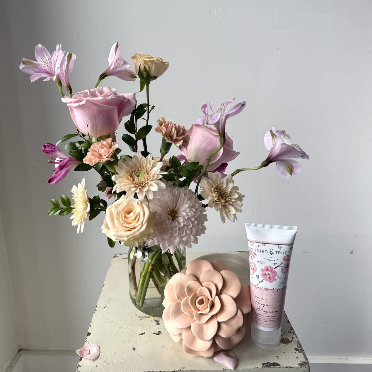 THE SELF CARE BUNDLE - Our small mason jar holds a simple, but lovely bouquet of seasonal flowers.  This dainty arrangement is accompanied by one of our Illume Ceramic Flower candles and Illume 3.5 oz Lotion hand-selected by one of our staff members.  Each arrangement and candle packaged in our signature white tissue and wrapped in our black, textured logo ribbon.   *Please note our floral and color palette changes from week to week.  All substitutions are of equal value.