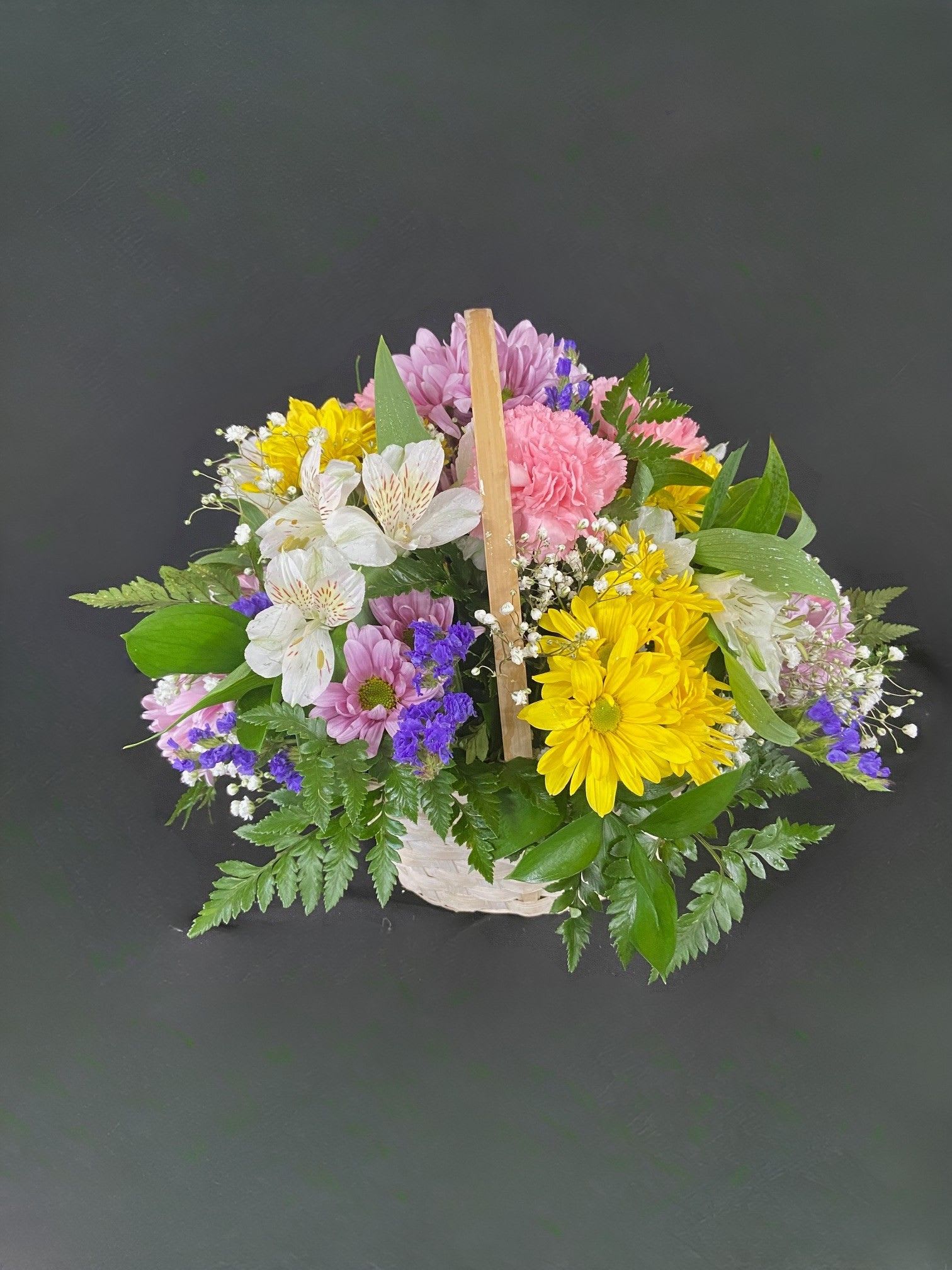 Basket of Cheer - A basket of bright, colorful flowers to pick up anyone's spirits. Includes Daisies, Carnations, Alstro, and seasonal filler flowers.