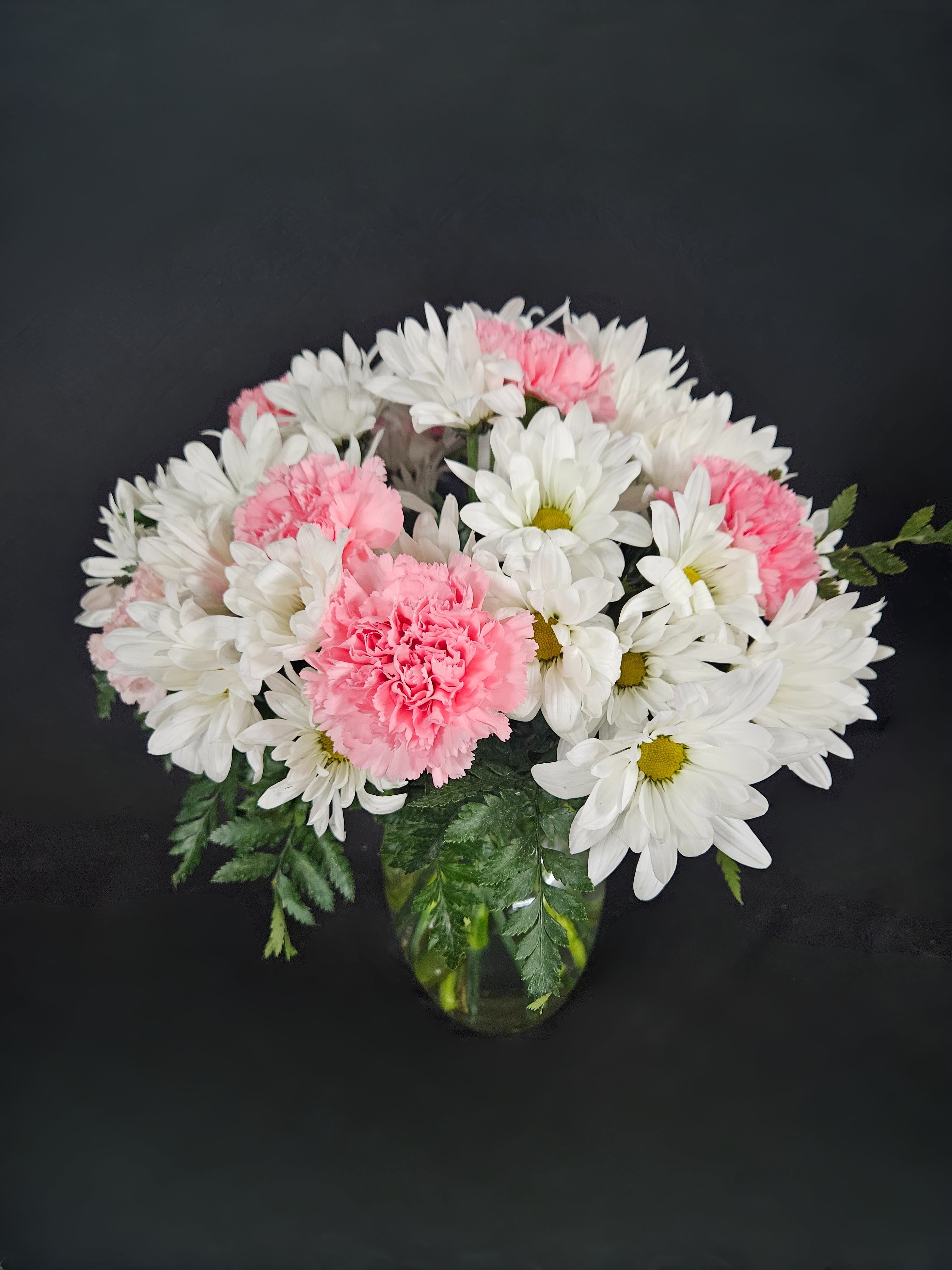 Rose &amp; Daisy Melody - An eye-catching bouquet of pink roses (deluxe &amp; premium sizes), pink carnations, and white daisies on a bed of greens. There is beauty in simplicity.
