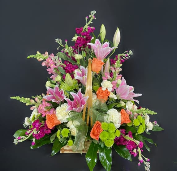 Summer's Picnic Basket - Treat yourself to a summer delicacy with Summer's Picnic Basket! This large woven basket is stuffed with lilies, roses, stock, daisies and other seasonal flowers until it's bursting at the seams. This is one picnic basket that Yogi Bear would be guaranteed to steal!