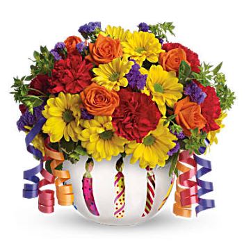 Brilliant Birthday Blooms - A frosted globe is decorated with birthday candles and filled with seasonal flowers such as yellow daisies, orange roses, red carnations, and multi color alstro. Celebratory streamers trail out of the sides with party favors peaking out the top.