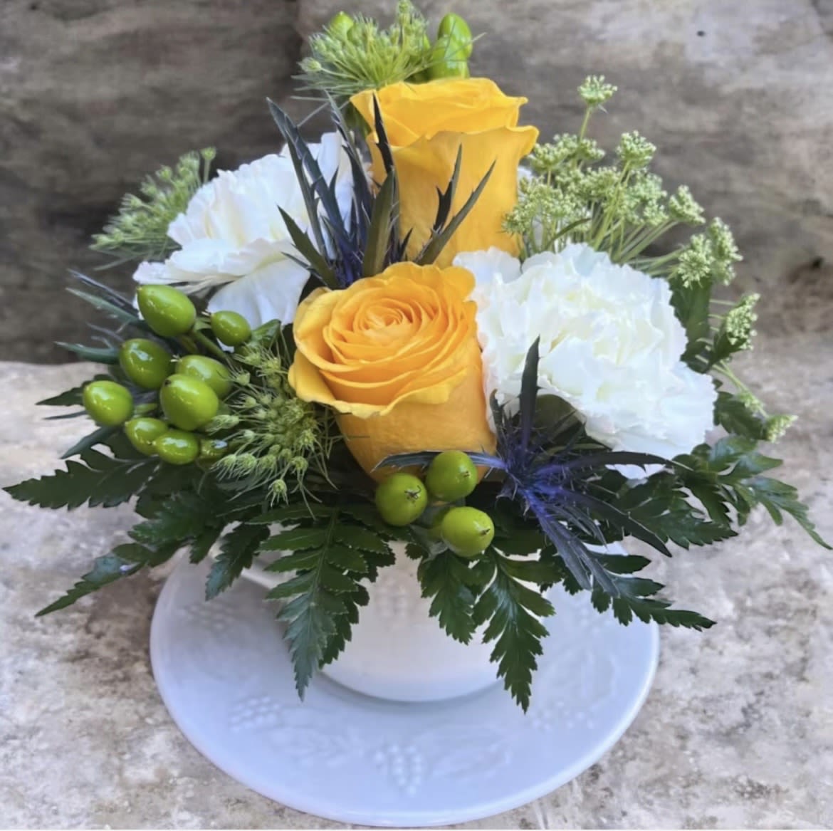 Sip of Sunshine Coffee Cup - This cute arrangement has queen Ann’s lace, yellow roses, thistle, hypericum and green carnations with greenery. 