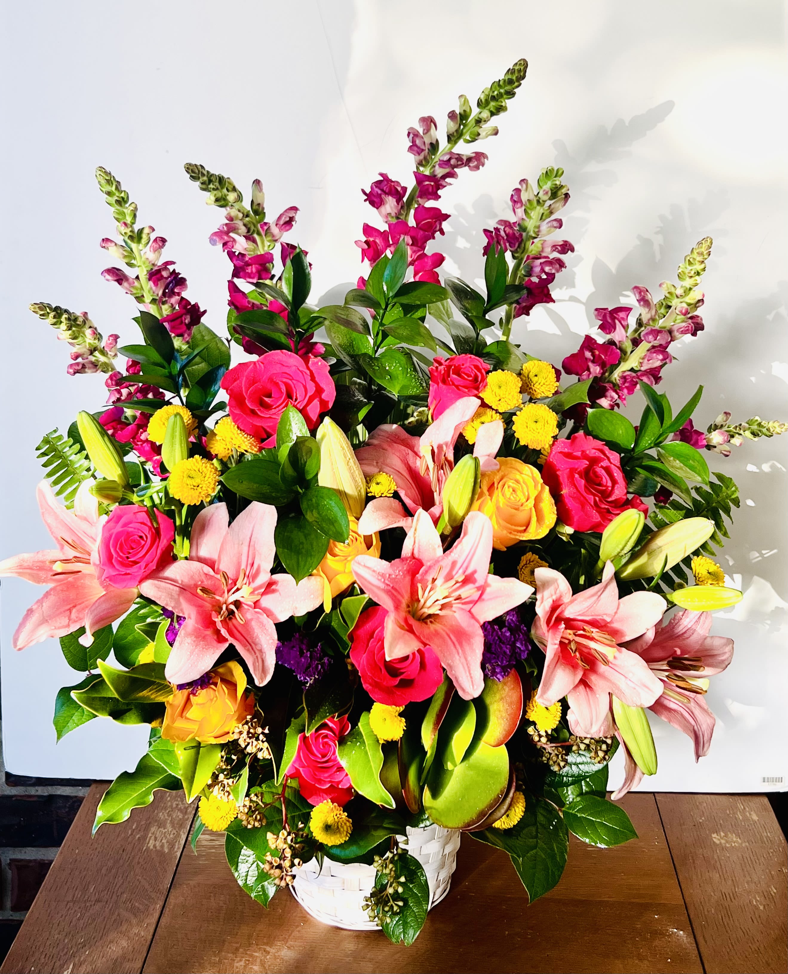 Grace In Bloom - Grace in Bloom  is a tall arrangement that radiates elegance and poise where gorgeous lilies open in soft, sweeping layers, while towering snapdragons add height and gentle movement.Grace in Bloom is ideal for making a statement at weddings, memorials, or formal events—where beauty and serenity take center stage.