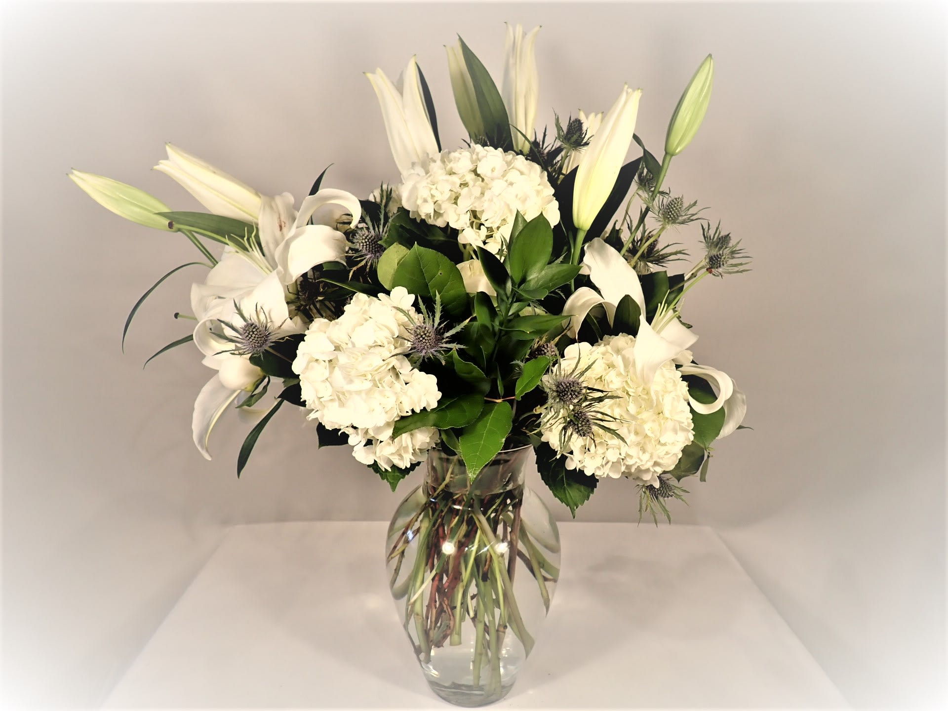 Snowball Effect  - White hydrangeas,  lilies, and more are beautifully arranged to show your support during difficult times or just because. 
