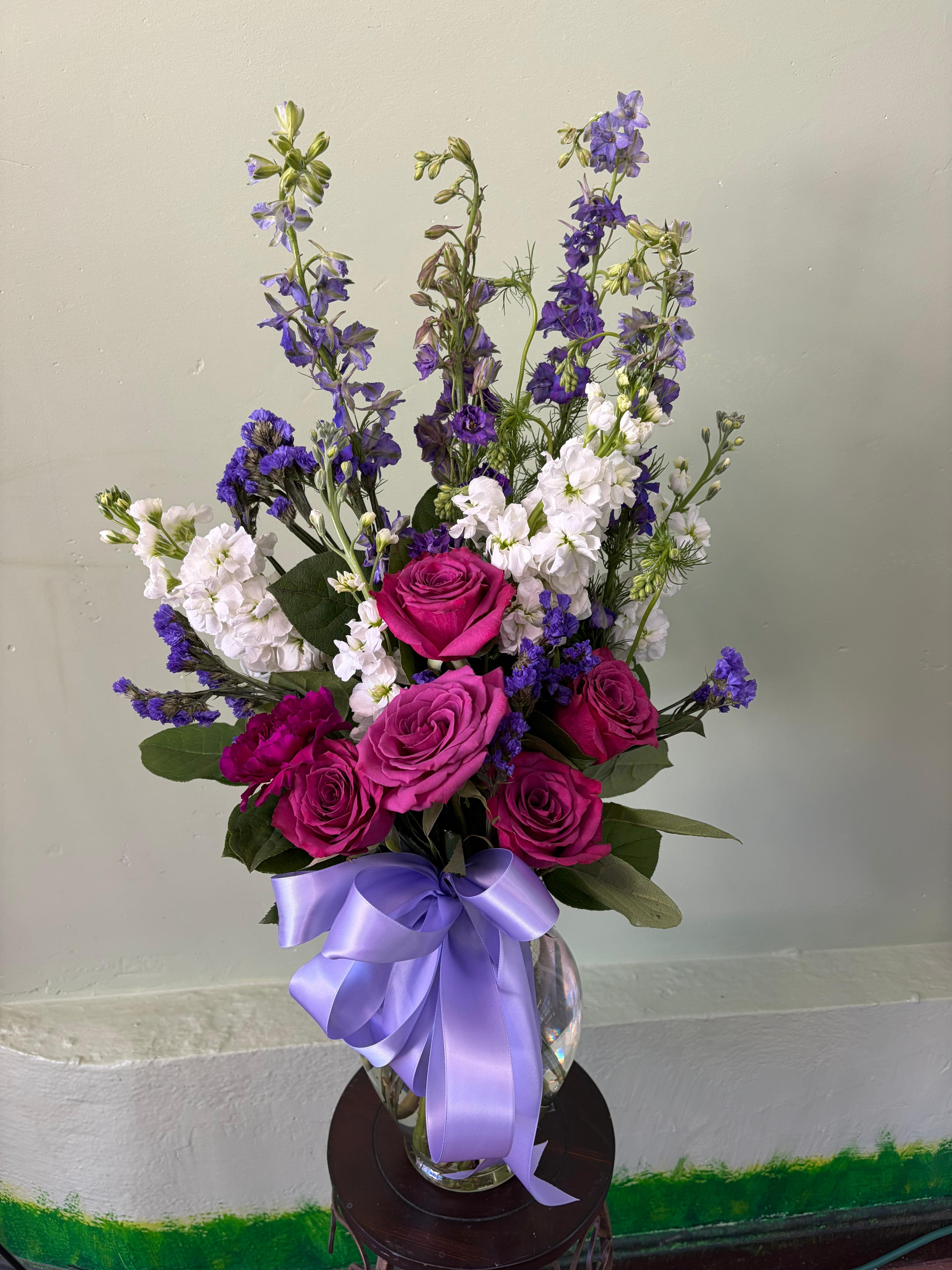 Lavender Garden Charm - A beautifully balanced design that brings together soft romance and fresh garden elegance. This arrangement features rich pink roses paired with delicate white blooms and airy lavender accents, creating a graceful blend of color and texture. Designed in a clear glass vase and finished with a soft lavender ribbon, it offers a light, uplifting feel—perfect for celebrating special moments or simply brightening someone’s day.
