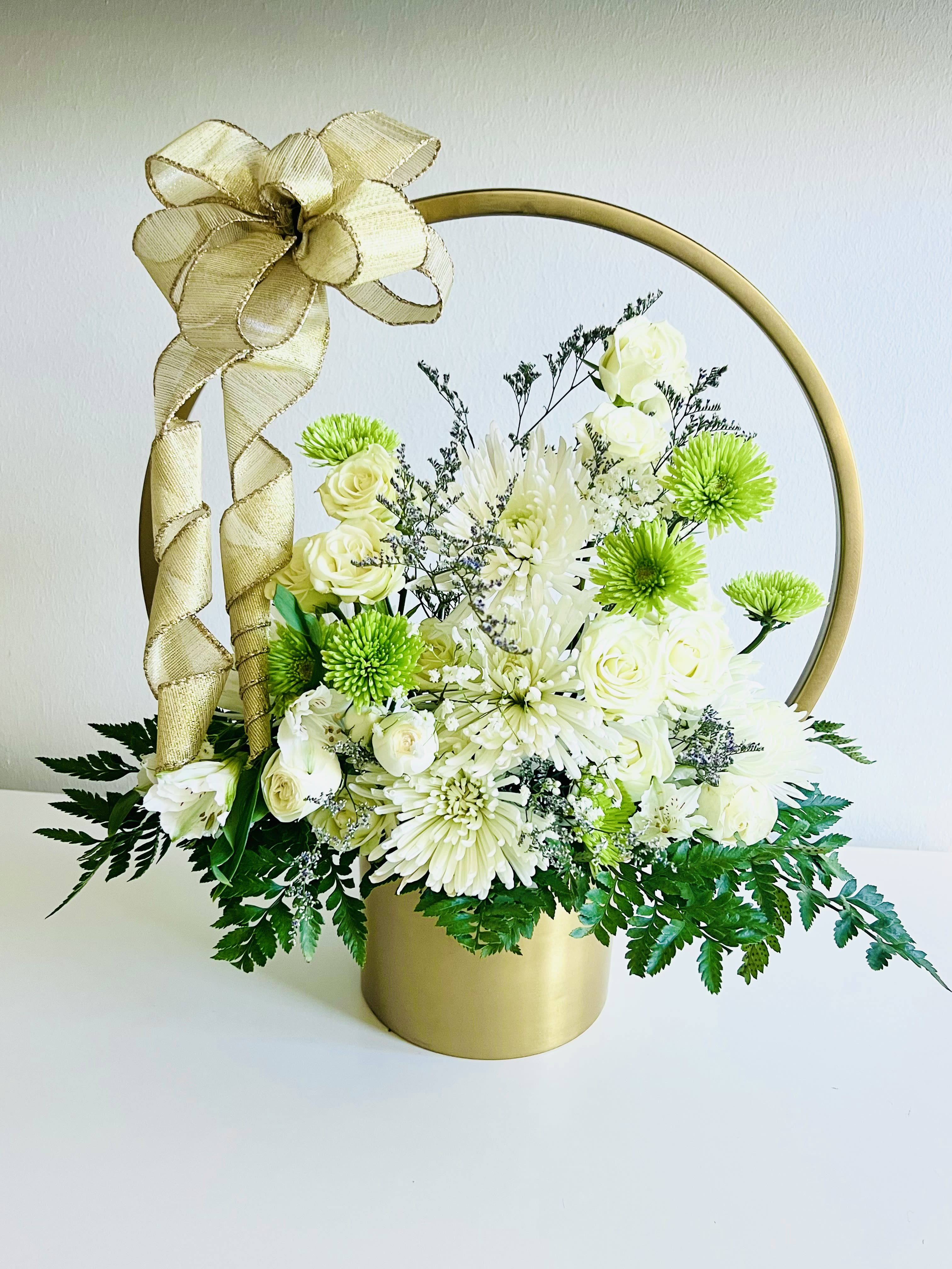 Heaven’s Whisper - Heaven’s Whisper is a serene blend of white hydrangeas, mums, roses, carnations  and seasonal foliage crafted to offer comfort in times of loss. Arranged in a muted gold metal basket that can be beautifully reused in the home, it adds a gentle touch of elegance to any memorial setting. A soft tribute that symbolizes purity, peace, and heartfelt remembrance when words are hard to find.