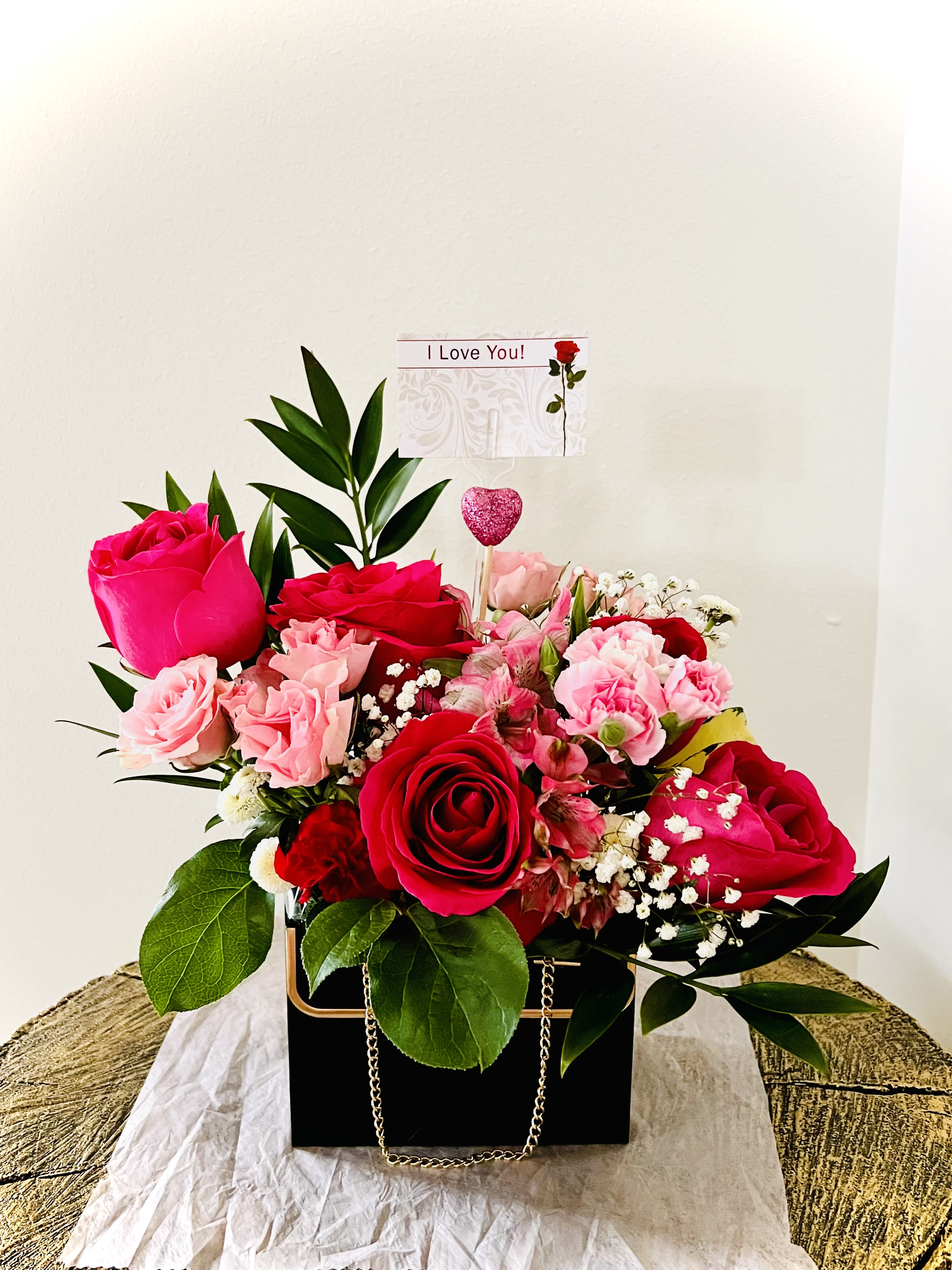 It's Love - Exquisitely crafted with premium hot pink roses, premium accents and seasonal greens , this absolutely adorable purse arrangement is sure to brighten up your loved one's day. it is a perfect valentines' gift .For same day delivery and Free Delivery Options Text or Call  832-973-1376.
