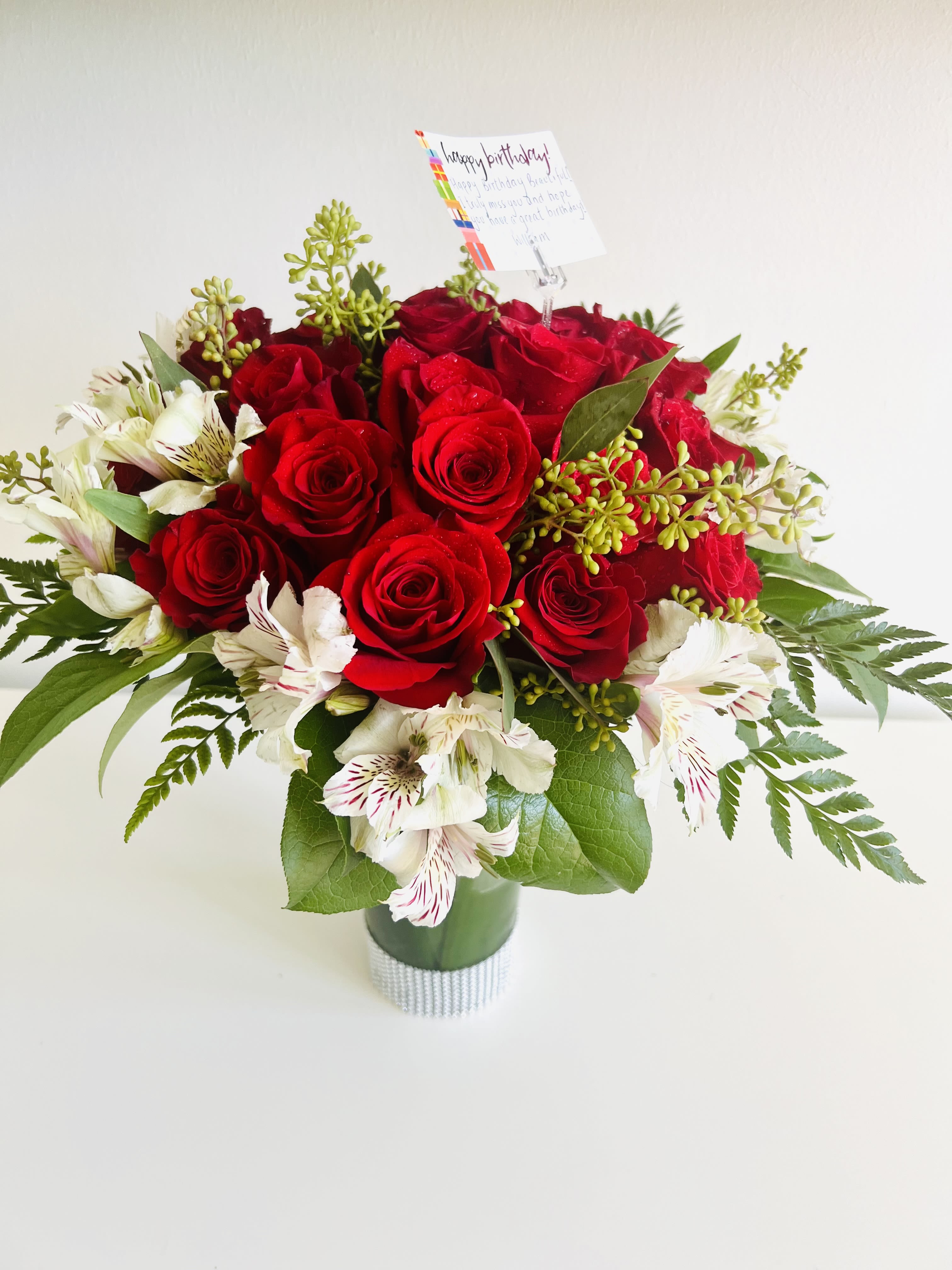 Whispers of Love - A stunning bouquet of 25 premium roses surrounded by lush seasonal foliage and elegant accents  radiates  grace, beauty, and heartfelt emotion.This arrangement is perfect for celebrating love, milestones, or simply making someone’s day unforgettable. 