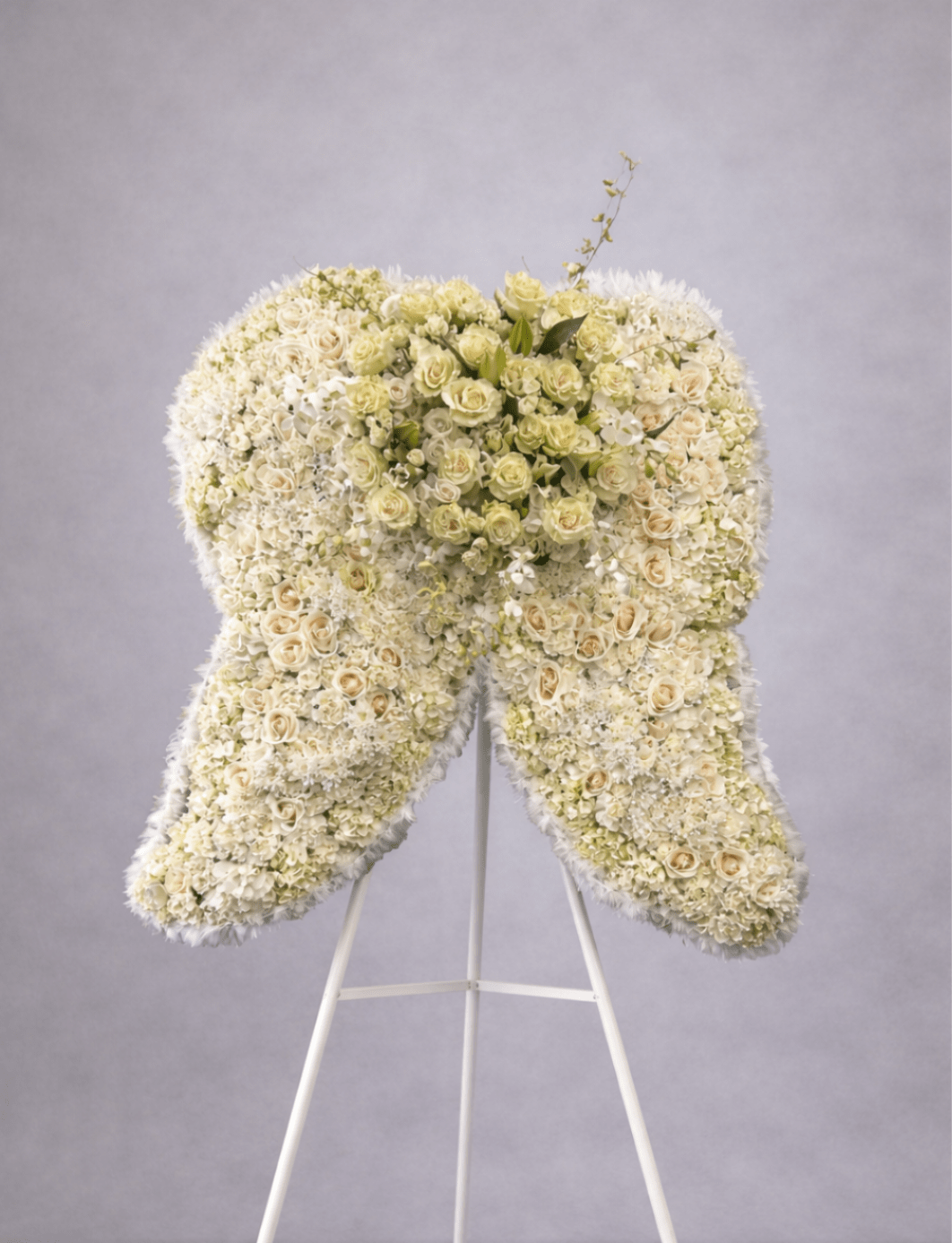 Large standing arrangement of white and cream flowers shaped like angel wings on a white easel.