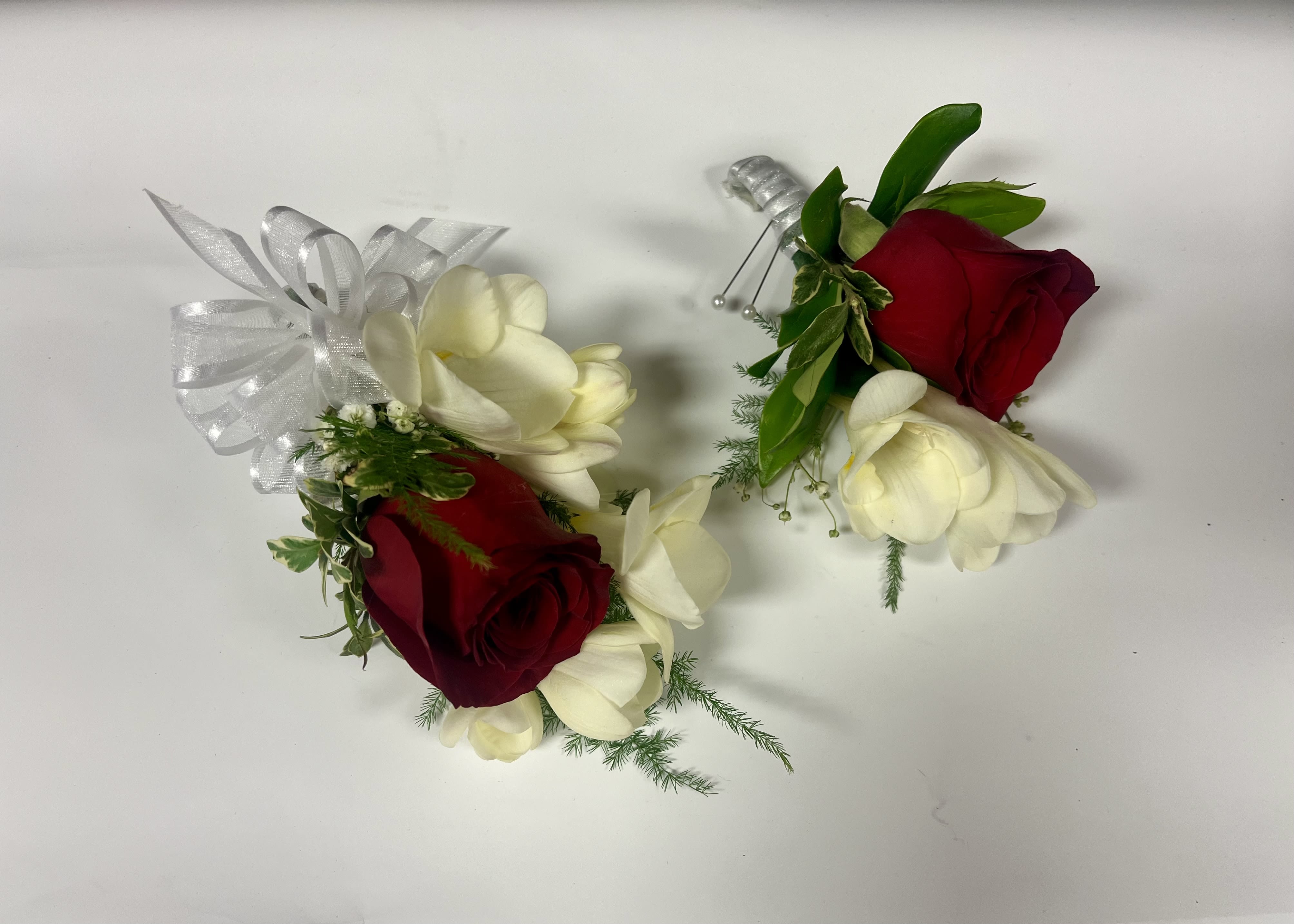 Freesia and Rose Corsage and Boutonniere - Pictured: Dusty sahara, red, and white rose with white freesia. Rose colors available: dusty sahara, red, white, ivory Freesia available only in purple or white.  PLEASE READ BEFORE PURCHASE Please specify color rose and ribbon in special instructions during check out. You can send a picture of the color dress/ tux to our email with order number: hello@flowerfinesse.com Choice of Pearl, Crystals, Feather, Glitter accents are available. Boutonniere only purchase regular Corsage only purchase deluxe Boutonniere and corsage set premium. Pick up only available. 
