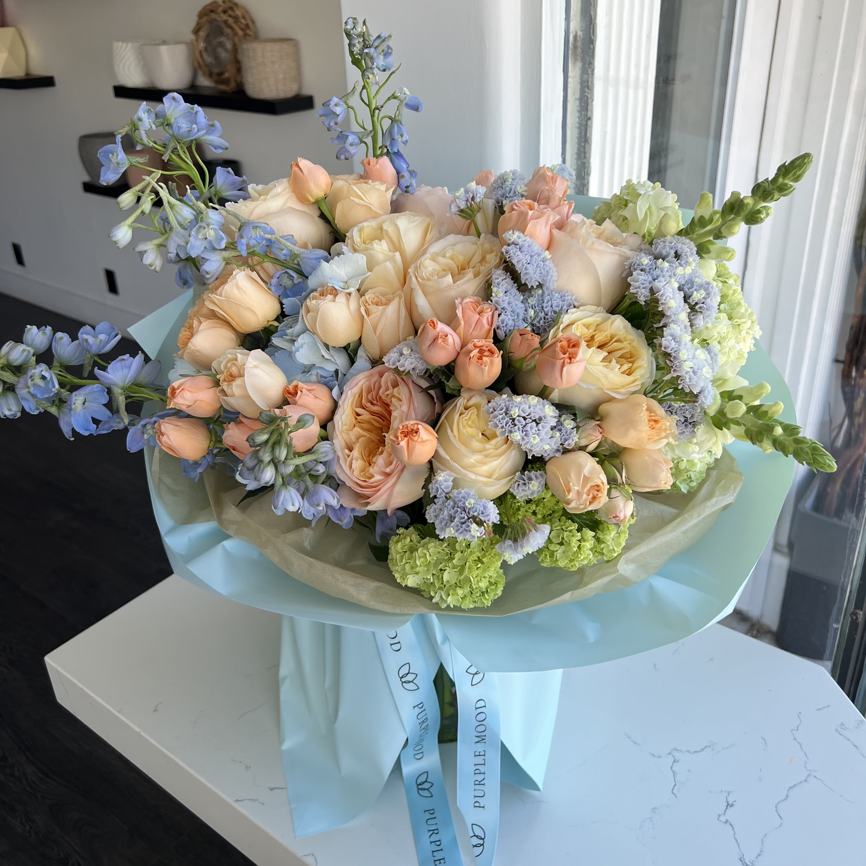 Sky Garden Bouquet - Sky Garden Bouquet Fresh, airy, and full of charm — the Sky Garden Bouquet feels like a piece of a summer morning sky. Its soft blue, peach, and pastel tones create a refreshing look that’s both elegant and uplifting.      •    Wrapped in a sky-blue design for a light, dreamy touch     •    Balanced blend of soft, cheerful colors     •    Available in Standard, Deluxe, and Premium sizes     •    Perfect for birthdays, celebrations, or simply to brighten someone’s day  VASE NOT INCLUDED