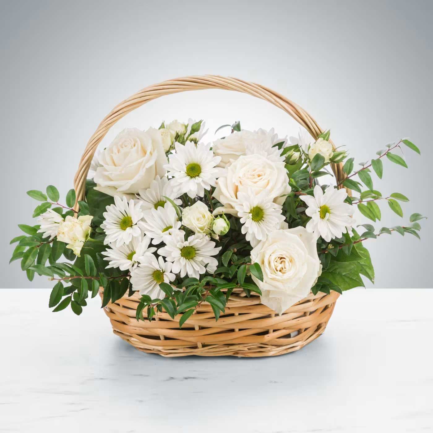 Pristine by BloomNation™ - A peaceful white and green basket featuring white daisy mums and white roses with greenery in a basket. Send your sympathies to the home with Pristine by BloomNation™  Approximate Dimensions: 14"D x 10"H