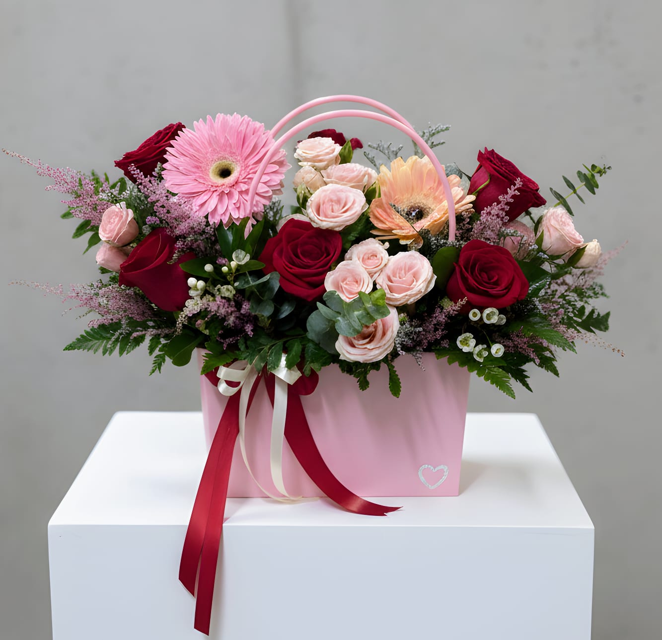 Blooming Purse Red and Pink - A chic floral arrangement featuring a mix of roses and seasonal flowers designed inside a stylish purse-shaped vase. Playful yet elegant, this unique design is perfect for birthdays, celebrations, and fashion-forward gifting.