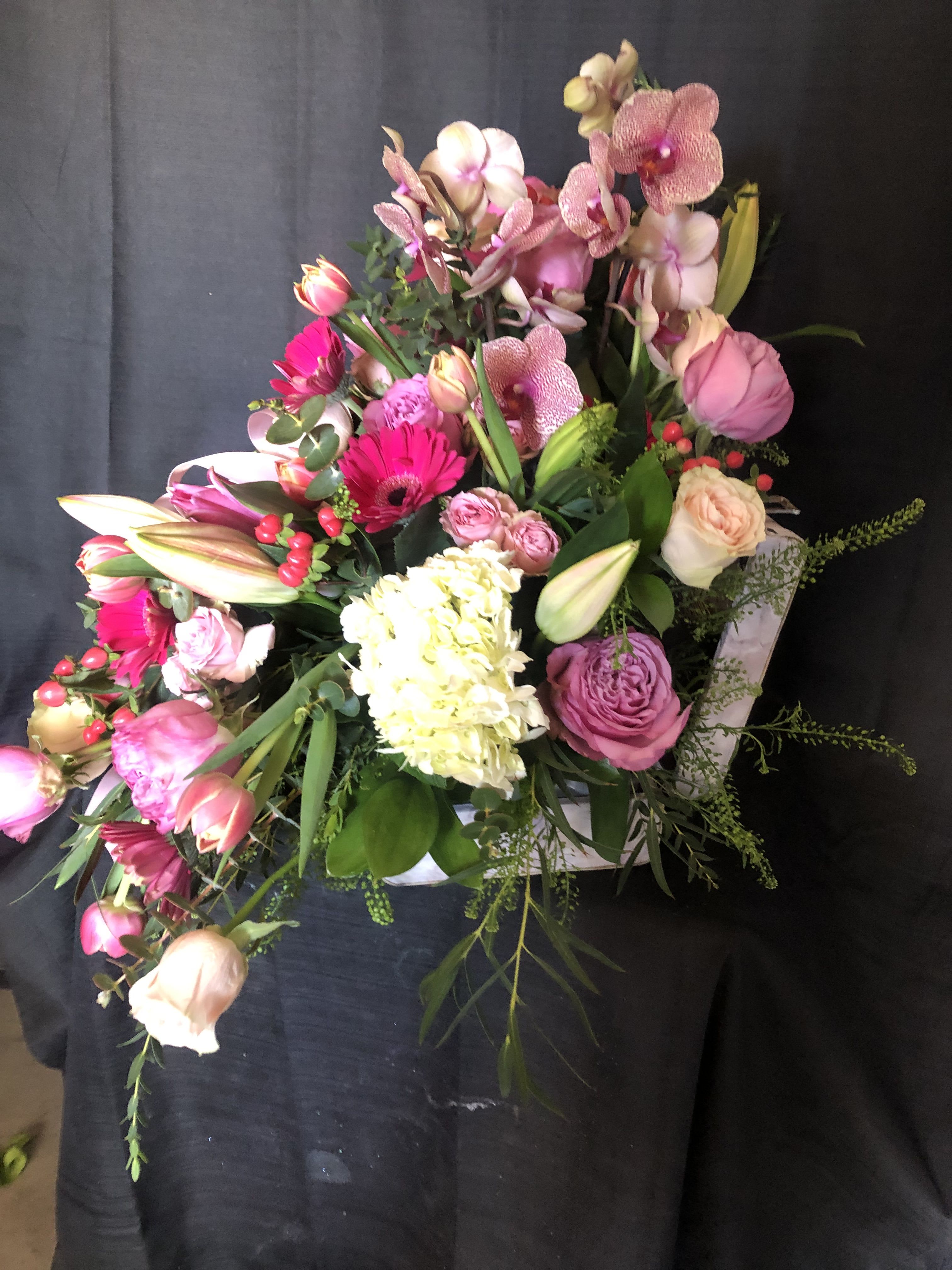 Asymmetrical pink and white flower arrangement in a white heart-shaped box