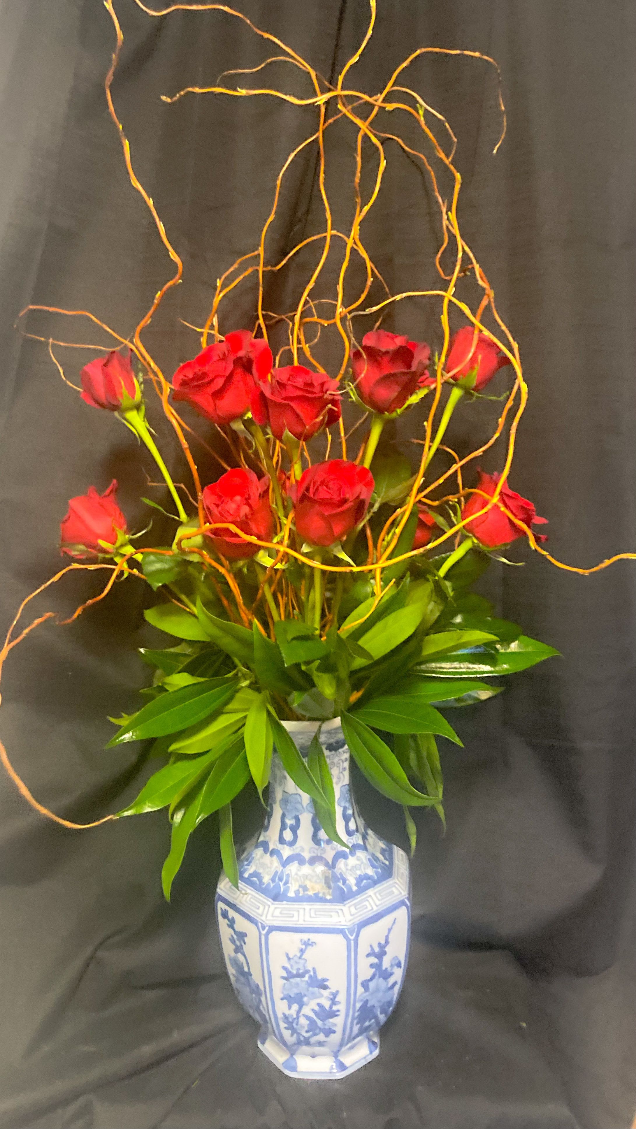 ASIAN ROSE ARRANGEMENT - A DOZEN 60 CM RED ROSES AND CURLY WILLOW ARRANGED IN AN ASIAN STYLE VASE.