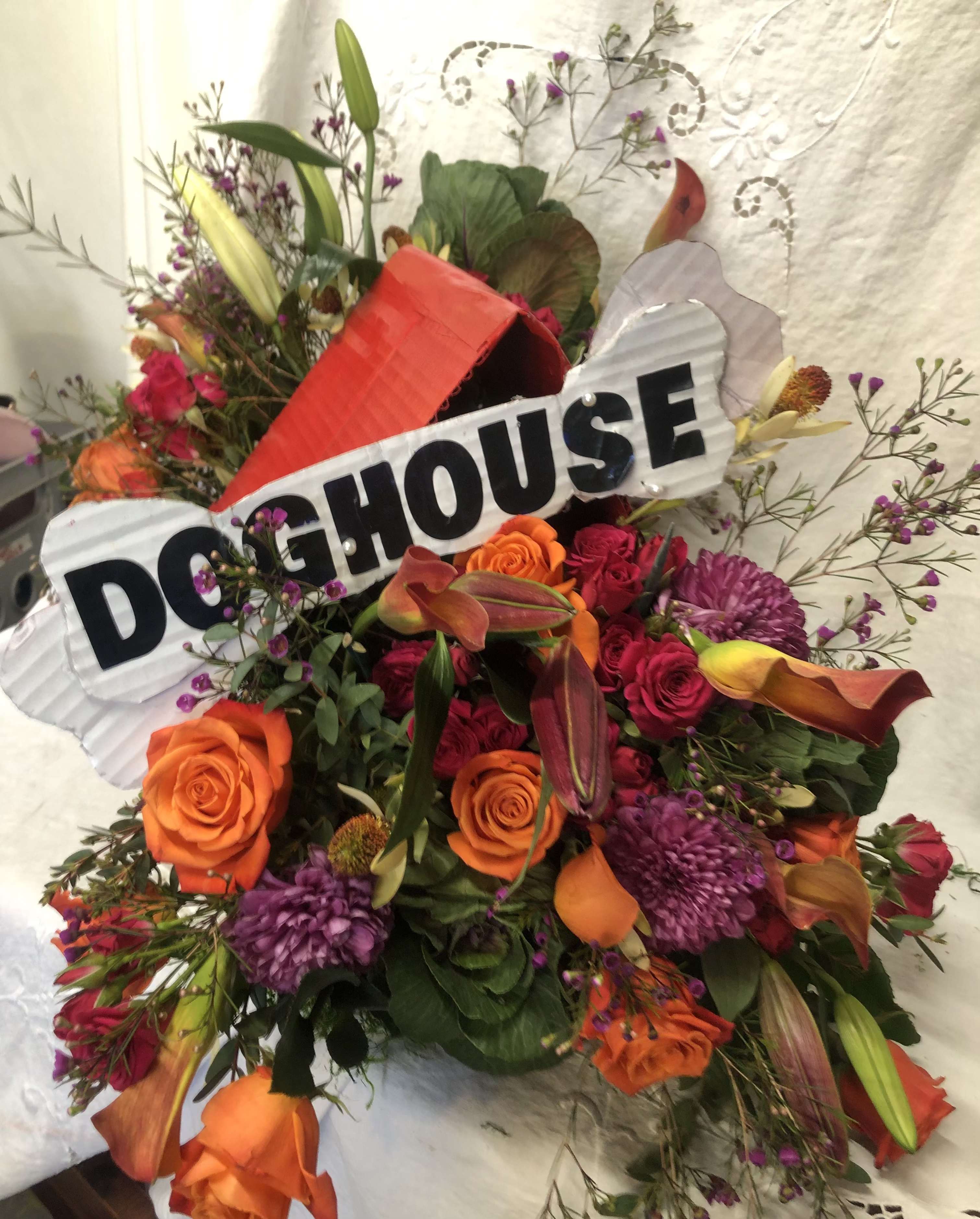 IN THE DOGHOUSE - ASSORTED BLOOMS BUILT INTO A DOGHOUSE WITH A BONE. SURE TO GET A SMILE