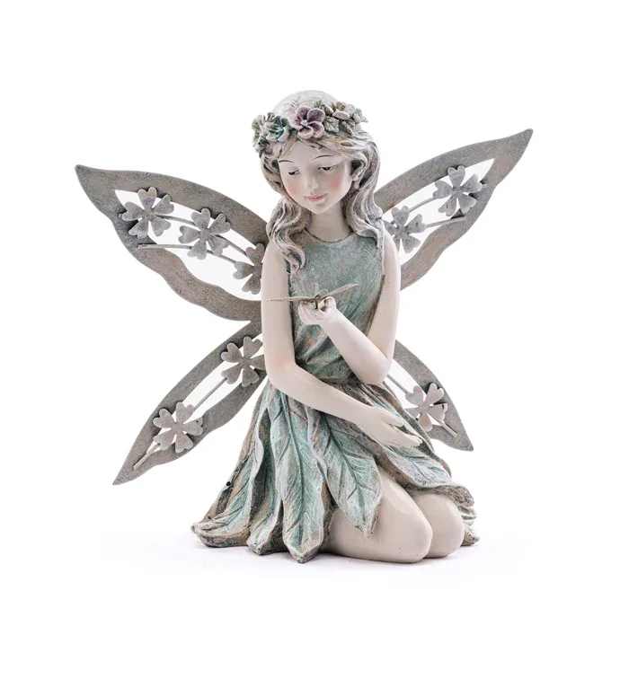 Kneeling Fairy with Dragonfly Figure - A kneeling fairy resin statue crowned in tiny blossoms brings a quiet, storybook charm to birthday bouquets and spring celebrations. This decorative fairy figurine and a little dragonfly accent is perfect for someone who loves whimsical garden touches - she'll feel seen and soothed by the serene pose and gentle color palette. The figurine wears a textured dress of overlapping leaf shapes in soft greens, paired with white and pink floral accents that echo the surrounding blooms. Her large, cutout wings-detailed with simple flower shapes-add airy texture while the wavy hair and floral crown enhance the arrangement's handcrafted look. The resin statue is sturdy enough to display with an arrangement or as a keepsake on a shelf or bedside table.  Ideal for birthdays, springtime hospitality, or a thoughtful "thinking of you" gift. This figurine is a lasting decorative accent. 8 Inches in Height and 8.5 Inches width