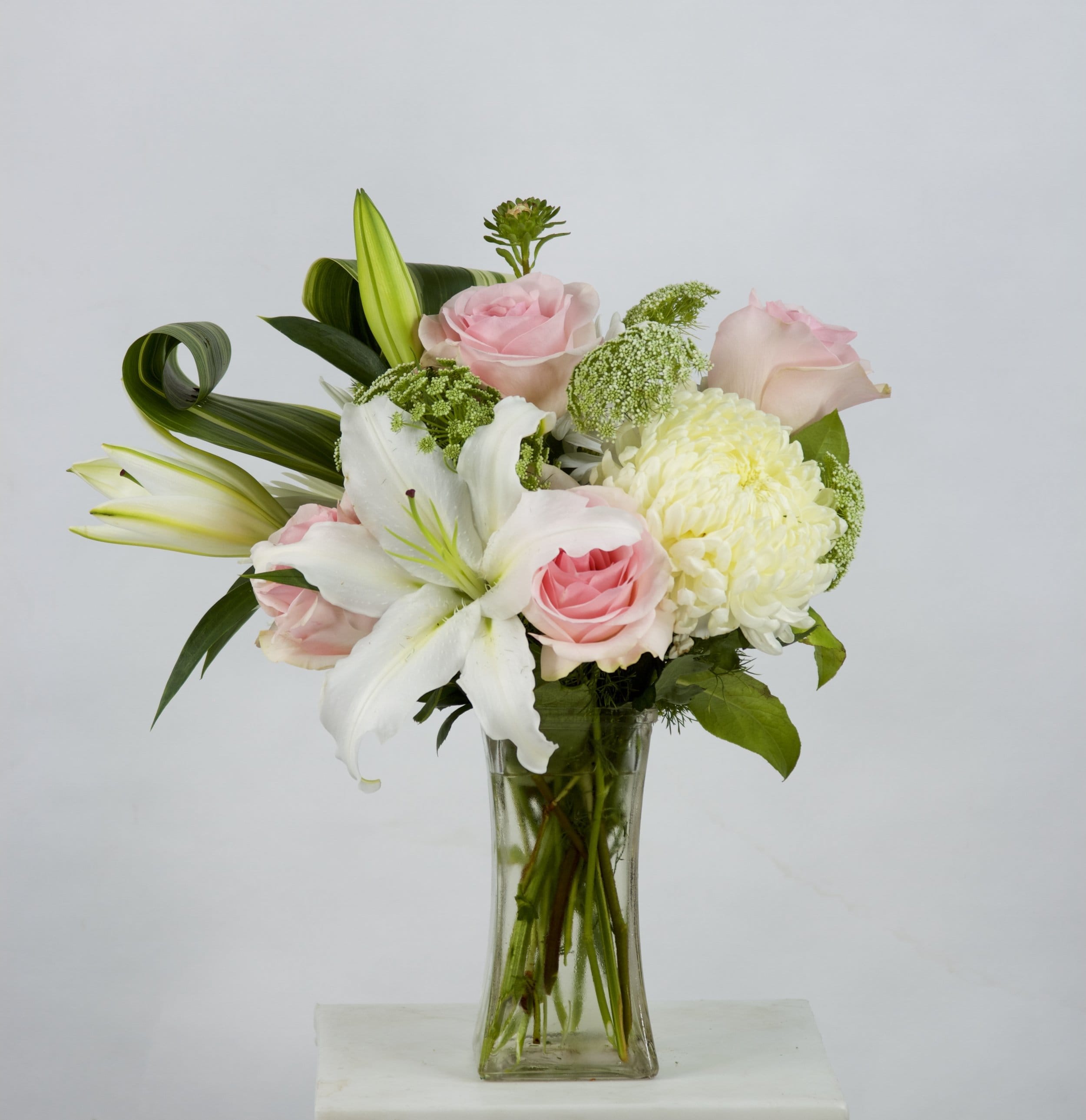 Simplicity - Flowers Included:  Roses Lilies Chrysanthemums Seasonal Flowers Seasonal Greens       Substitutions may be necessary to ensure your arrangement or specialty gift is delivered in a timely manner. The utmost care and attention is given to your order to ensure that it is as similar as possible to the requested item (Please note that some flowers and colors may vary due to seasonality.)