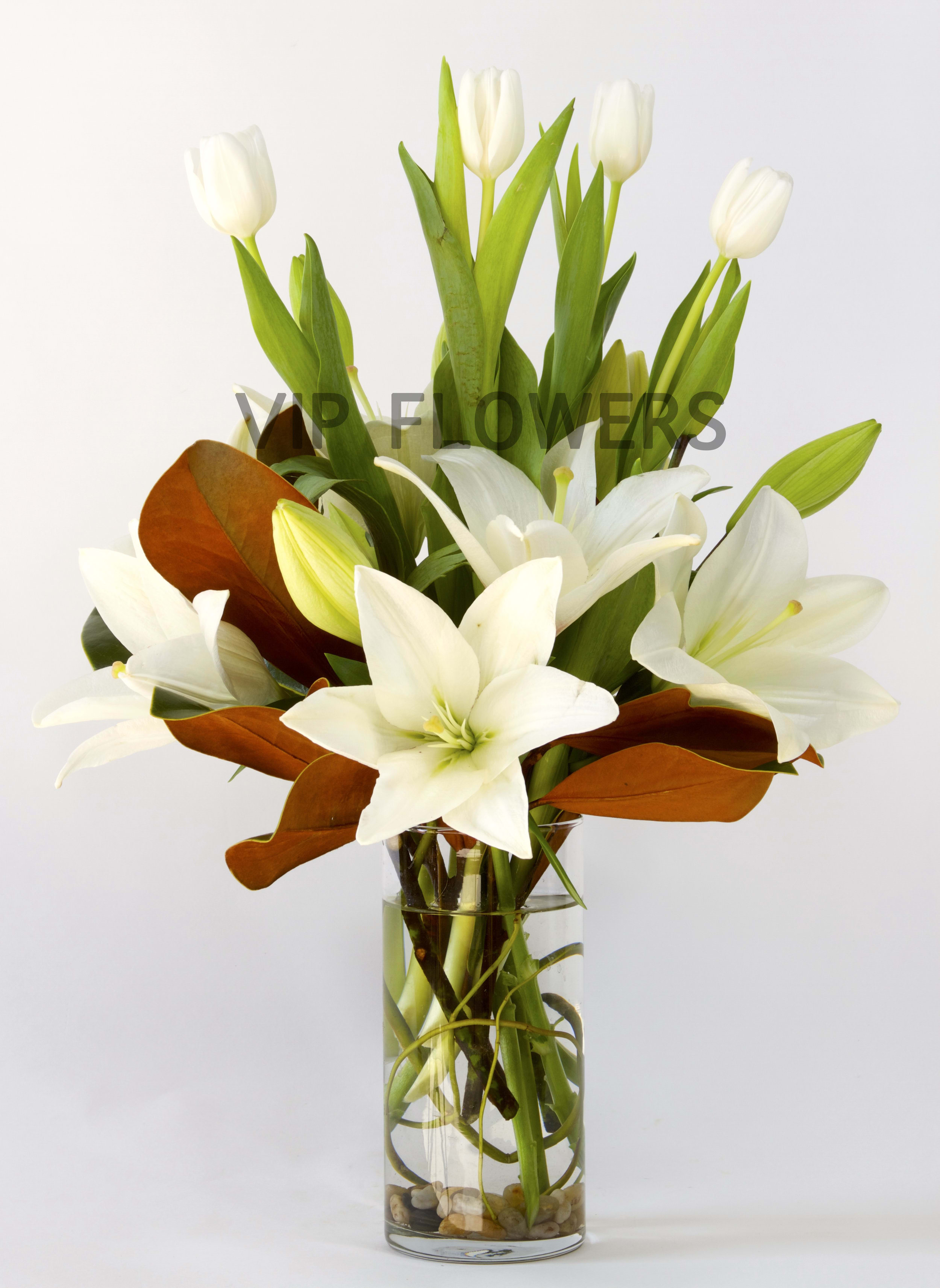 White lilies and tulips in a clear glass vase