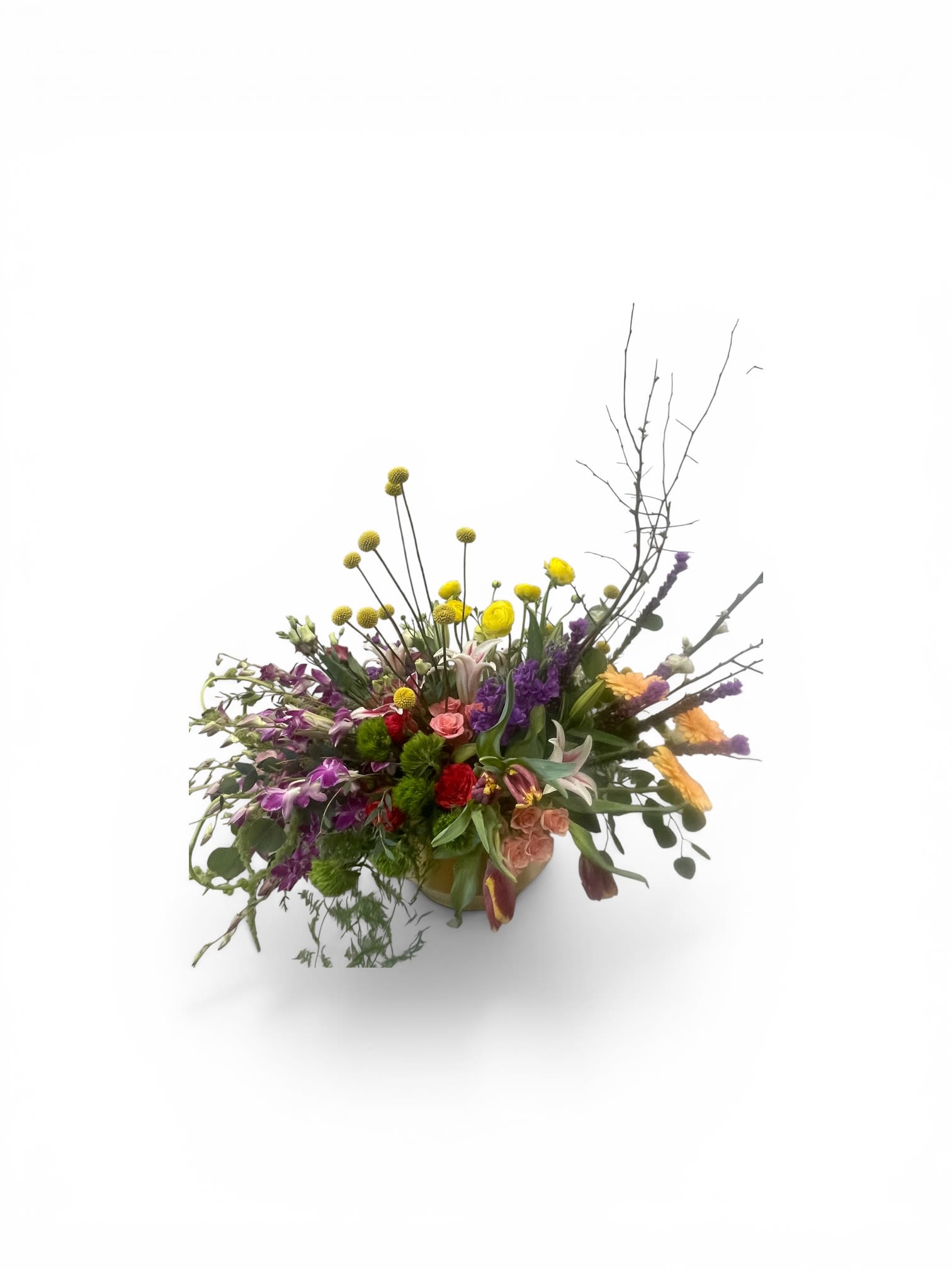 Forever Blooms by Petal Perfection  - A lively cascade of color greets the eye in this low, elongated flower arrangement-perfect as a birthday bouquet, Mother's Day gift, anniversary surprise, or bright "thinking of you" pick-me-up. The round ceramic vase holds a whimsical, garden-inspired mix that reads celebratory and creative, the kind of piece that makes the person you're sending it to feel genuinely seen and cheered.  Clusters of peach and red roses and lilies form a lush, fragrant center, surrounded by lavender and purple stems, dendrobium orchids, chrysanthemums, and mixed seasonal blooms in white, yellow, pink, blue, orange and green. Bright yellow button-like flowers and bare branches add vertical interest while trailing stems sweep outward for an airy, artful silhouette-ideal for mantel, dining table, or office reception. This arrangement arrives ready-to-display in its ceramic vase; choose it for birthdays, get-well wishes, housewarmings, graduations, sympathy and funeral settings, or simply as a joyful everyday accent that brings color and texture to any room.