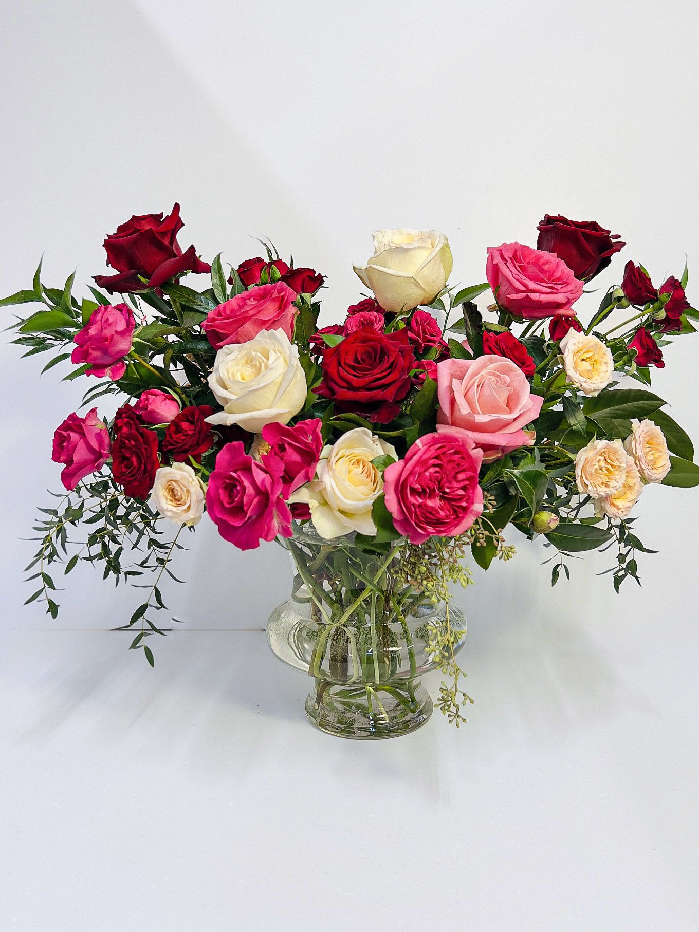 Roses En Masse - This luxurious display features an abundance of rich, velvety roses and garden roses in a symphony of colors, ranging from playful pinks to deep, romantic reds.
