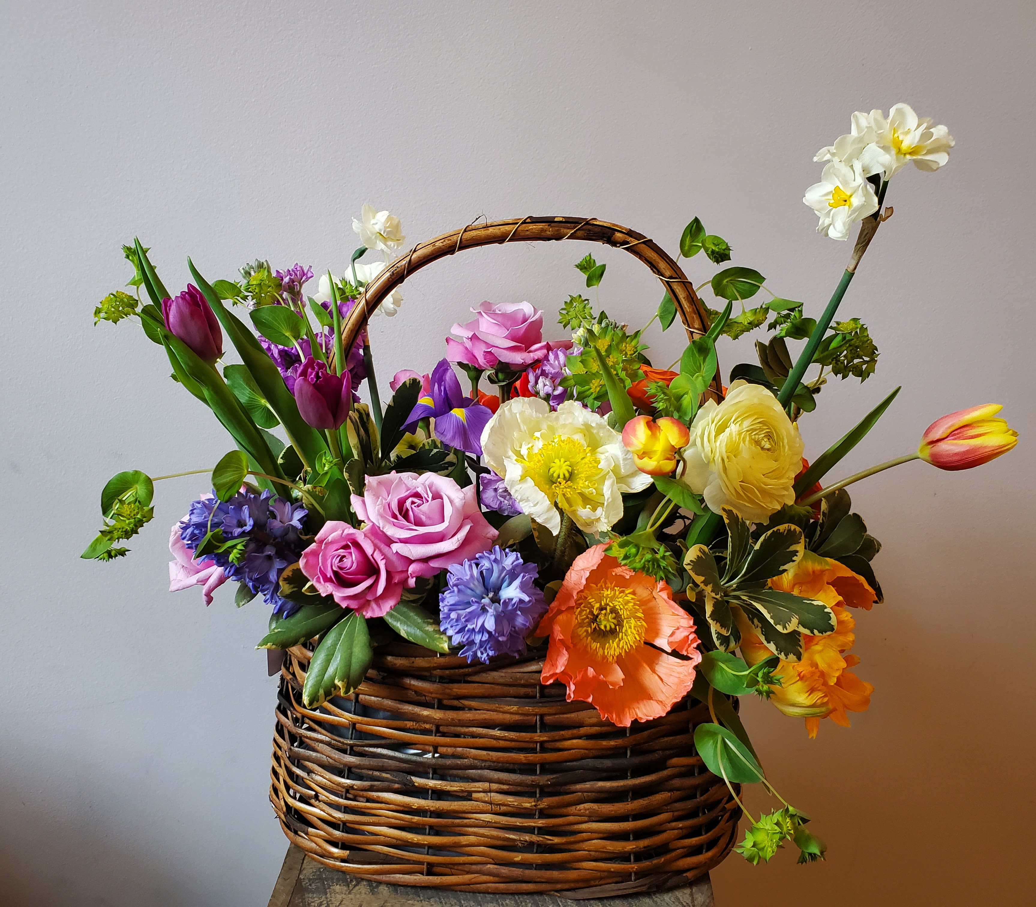 Easter Basket - This bountiful basket of blooms is sure to put a spring in your step!  Containing roses, tulips, poppies, and other early spring delights in a beautiful woven basket.  Arrangement measures approximately 15 x 15".