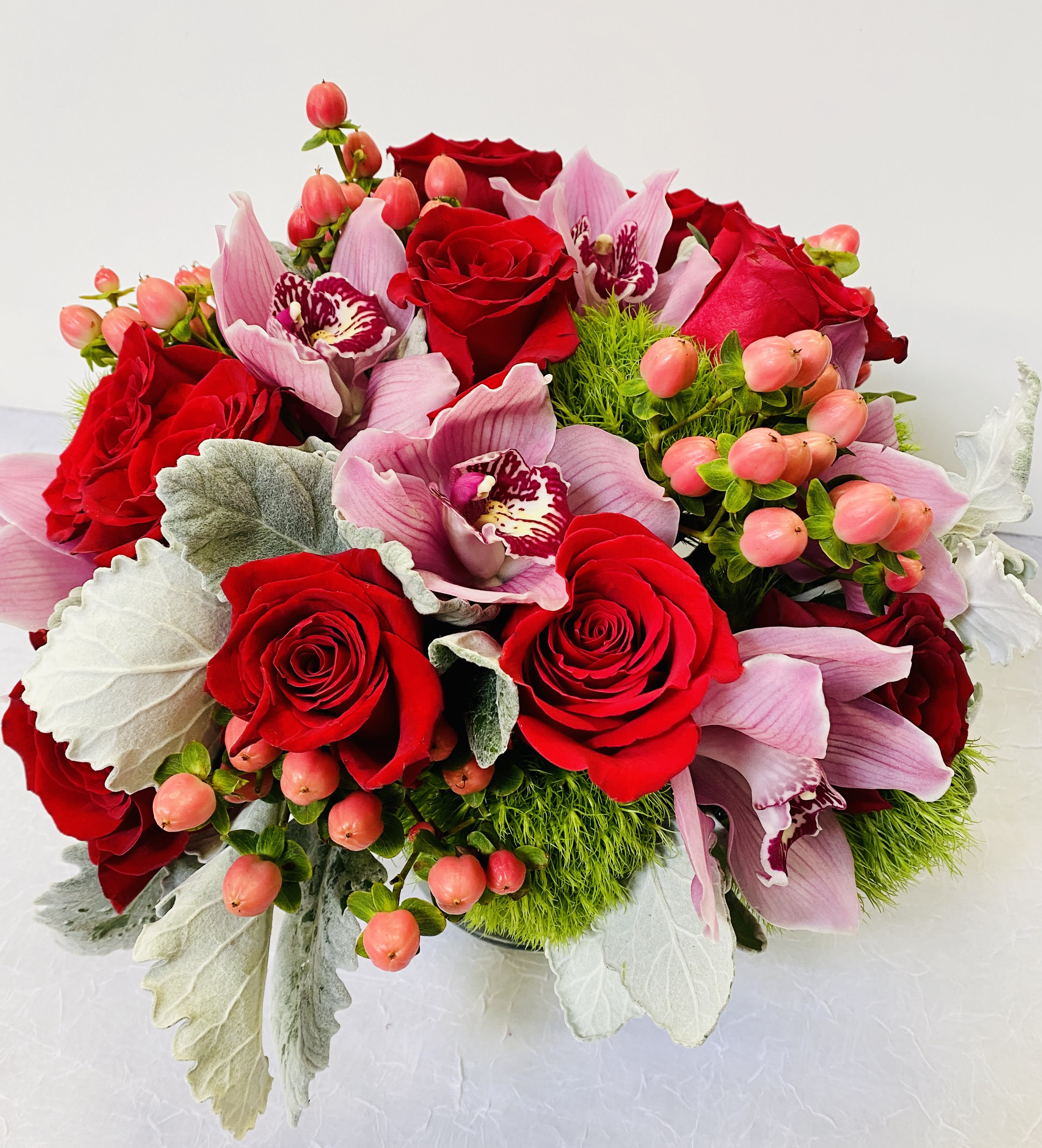 Holidate - Beautiful arrangement in a glass vase with red roses, , pink cymbidium ,   hypericum 