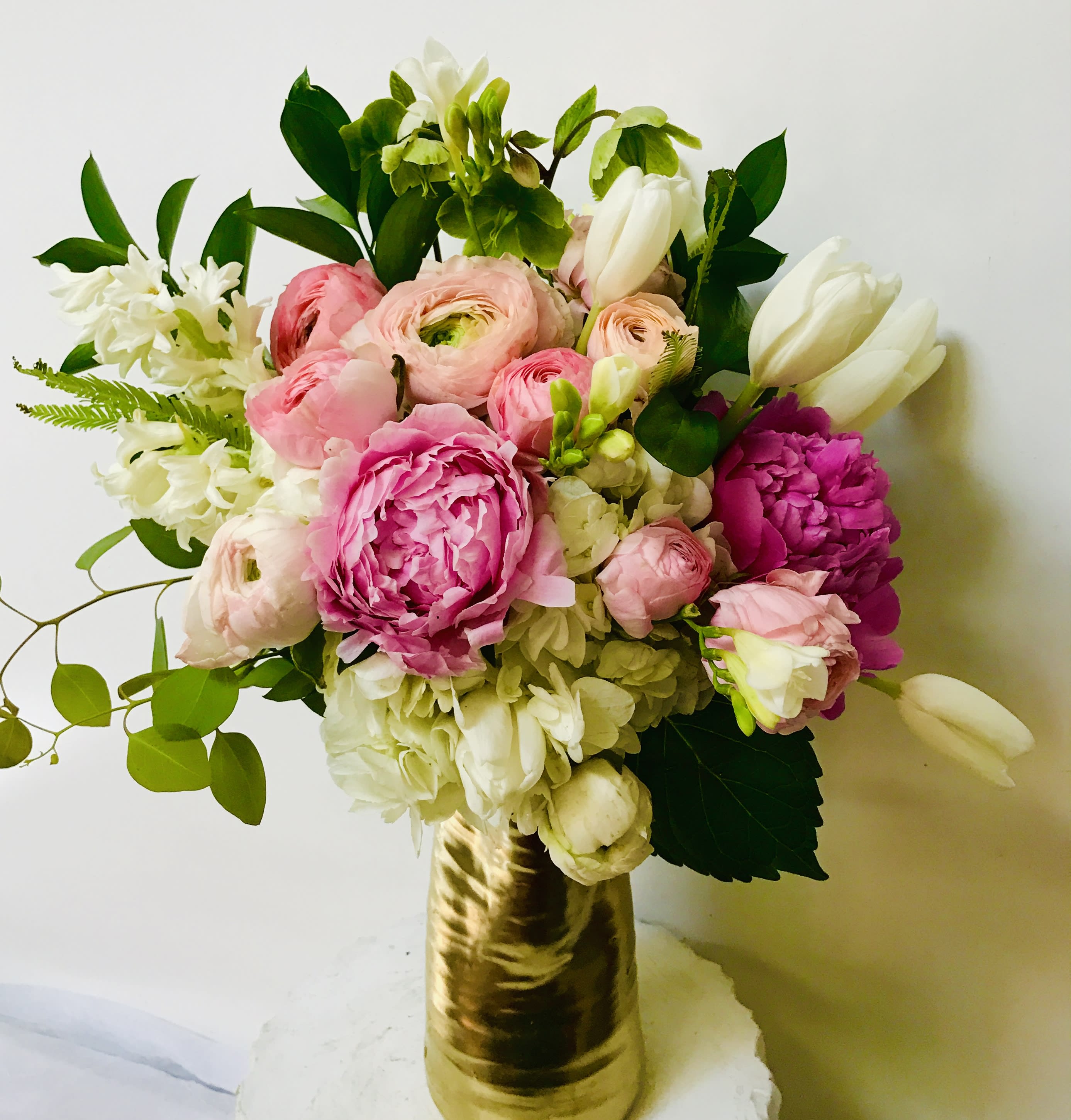 Legends of the Fall - Introducing Legends of the Fall by Jane's Roses, a breathtakingly romantic arrangement that perfectly blends classic elegance with modern flair. Handcrafted by a leading San Francisco Florist, this luxurious bouquet is a symphony of blush, cream, and magenta, evoking a sense of timeless beauty.  The design is centered around the lush, multi-petaled drama of Pink Peonies and delicate blush-to-cream Ranunculus, providing a dreamy texture and soft, captivating color palette. Pure white Tulips stand tall, adding striking lines and crisp contrast, while clusters of fragrant white Hyacinth infuse the air with a sweet, intoxicating perfume.  The base is built upon fluffy white Hydrangea, lending volume and a cloud-like softness. Fresh, bright green accents, including leafy stems and delicate trailing greens like Eucalyptus, complete the look, making the vibrant colors pop. Presented in a striking gold-toned vessel, this arrangement makes an unforgettable statement.  Perfect for a grand romantic gesture, a sophisticated centerpiece, or a luxurious gift. When you seek the highest quality flowers and exceptional design, trust your local San Francisco Florist. Order Legends of the Fall today and experience the artistry of Jane's Roses.