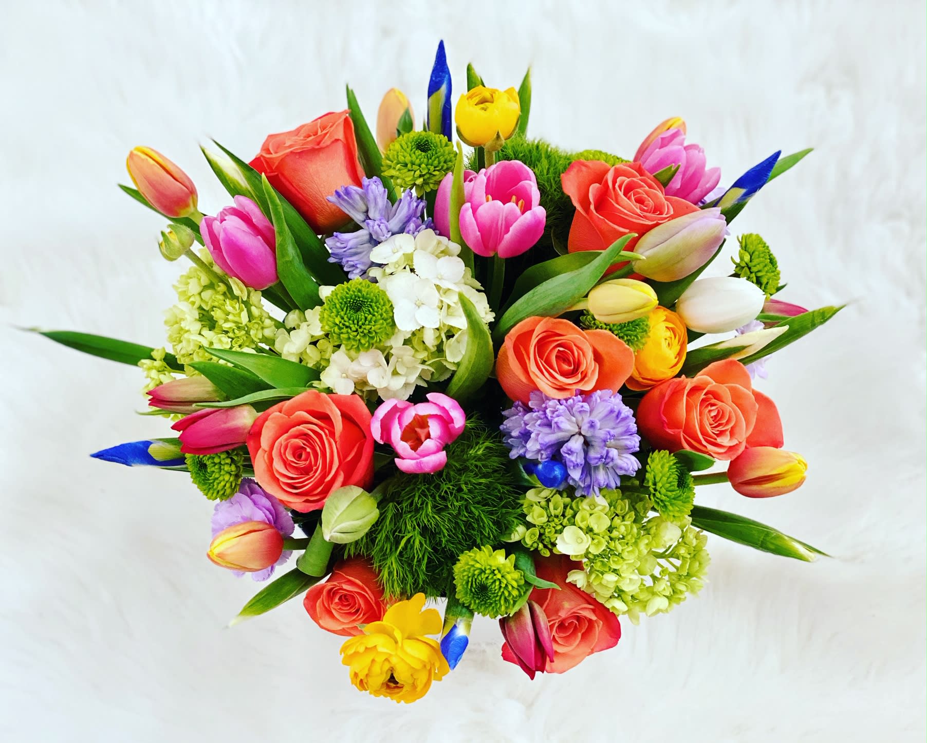 Magic City ™ - Gorgeous and vibrant spring flowers cluster in a large glass vase.