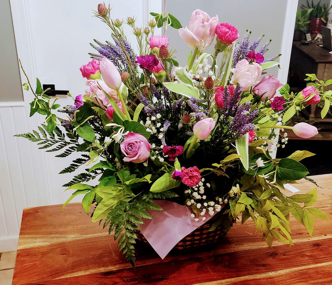 Lavander Kiss - Beautiful roses and tulips in shades of purple with a mix of blooms in shades of pink surrounded by lush greenery.