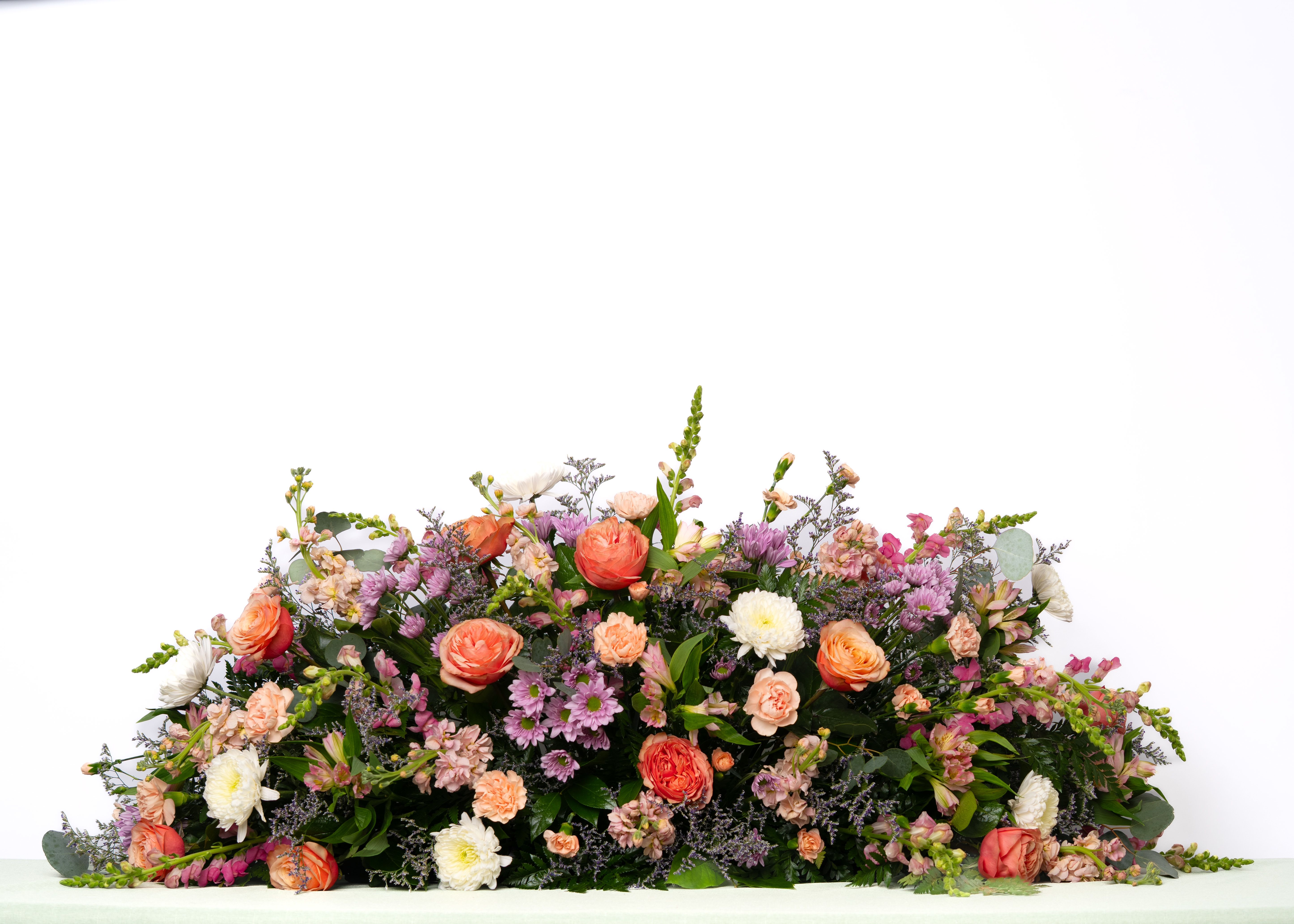 Our Hope Collection: Full Casket Spray in Pastel Blooms - Soft and expressive, this large, pastel casket spray offers a gentle and heartfelt tribute. Designed with seasonal blooms in harmonious tones, it brings warmth and beauty to the service.  Each arrangement is thoughtfully designed using the freshest blooms available. Flower varieties may vary based on availability while maintaining the overall style, color palette, and value.  Approximate Dimensions of Floral Tribute: 18" tall x 48" wide  Color &amp; Customization: Need a custom color scheme? Contact us for more information. Our most popular palettes include whites, whites and greens, whites and blues, pinks and whites, pastel shades, and colorful designs.  Delivery: All sympathy pieces are hand-delivered by the Schultz Floral team.