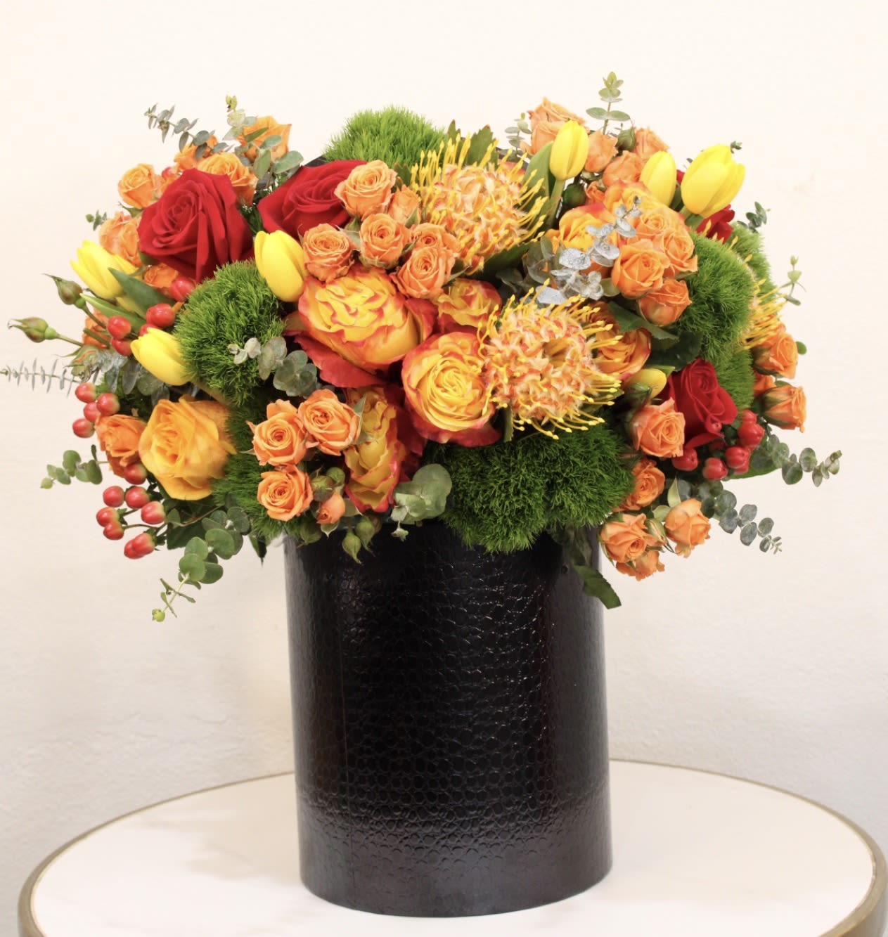 Golden Sunset - Experience timeless elegance with our Golden Sunset, a rich and vibrant floral design featuring premium seasonal blooms in warm shades of orange, yellow, and deep red. Designed in a modern black vase, this arrangement brings a perfect balance of sophistication and bold beauty, making it ideal for birthdays, celebrations, or luxury gifting. Each arrangement is handcrafted with attention to detail to ensure a high-end floral experience that stands out.  Same-day flower delivery available across: Beverly Hills, Bel-Air, West Hollywood, Beverly Grove, Culver City, Hollywood Hills, Hollywood, Santa Monica, Studio City, Sherman Oaks  The arrangement shown in the photo is the Deluxe size.
