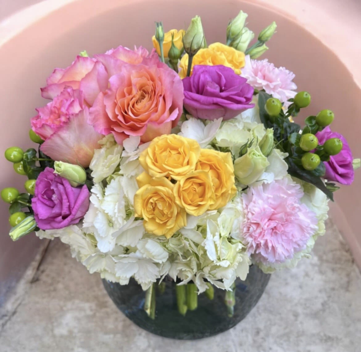 Blushing Beauty  - This arrangement is in a 8 inch bubble bowl filled with hydrangeas, roses, carnations, hypericum, spray roses and lisianthus.