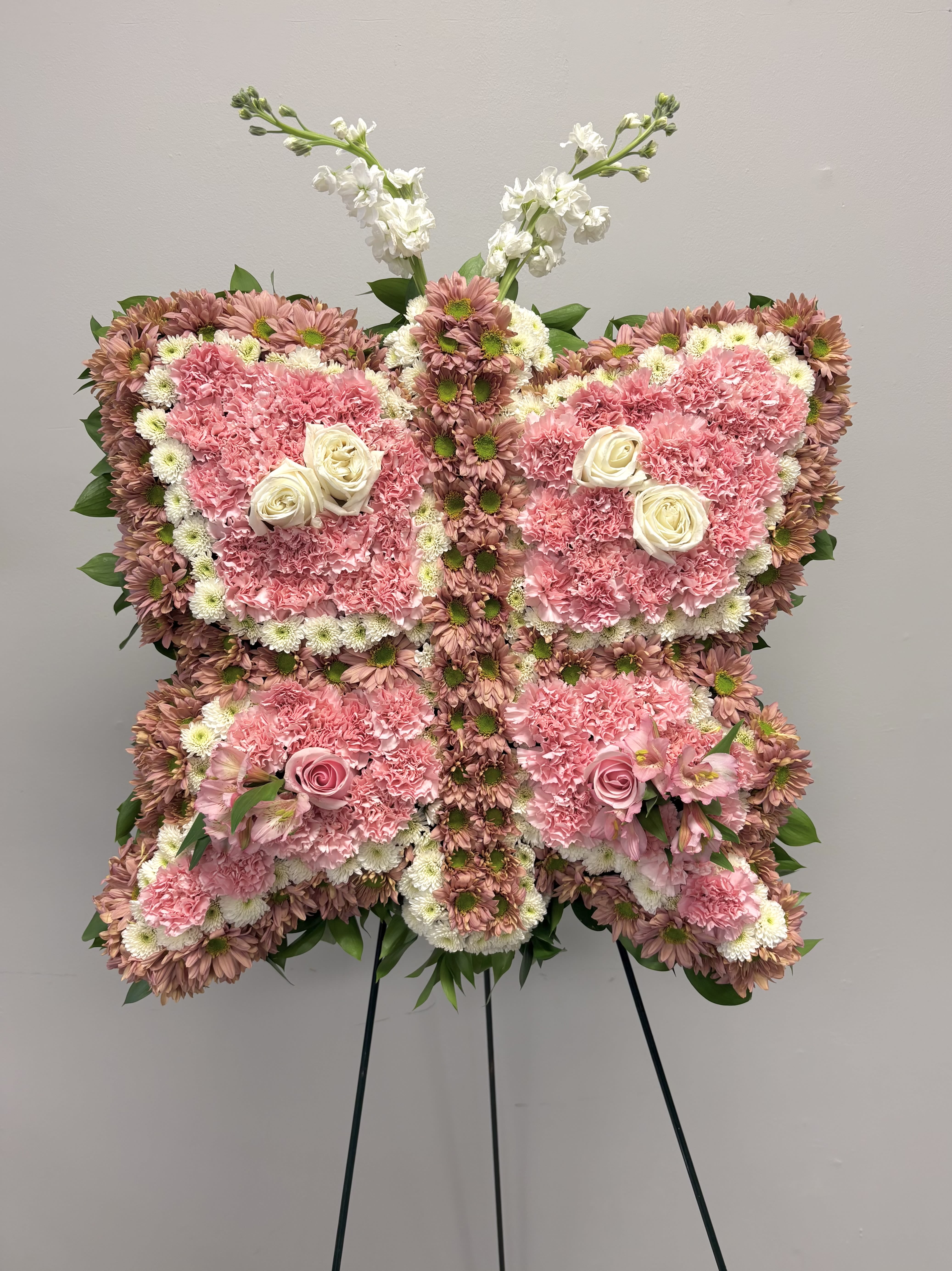 THE BUTTERFLY MESSENGER - A unique sympathy piece to honor a free spirit  who lived a life in touch with nature. This piece includes pink daisies, white mums, pink carnations  pink alstromeria, and pink and white roses.  If you have a shape in mind for a custom piece such as this whether it be an animal, sports item or something else,  call our  store so we can discuss possibilities. 732-842-3933  info@shopfineflowers.com