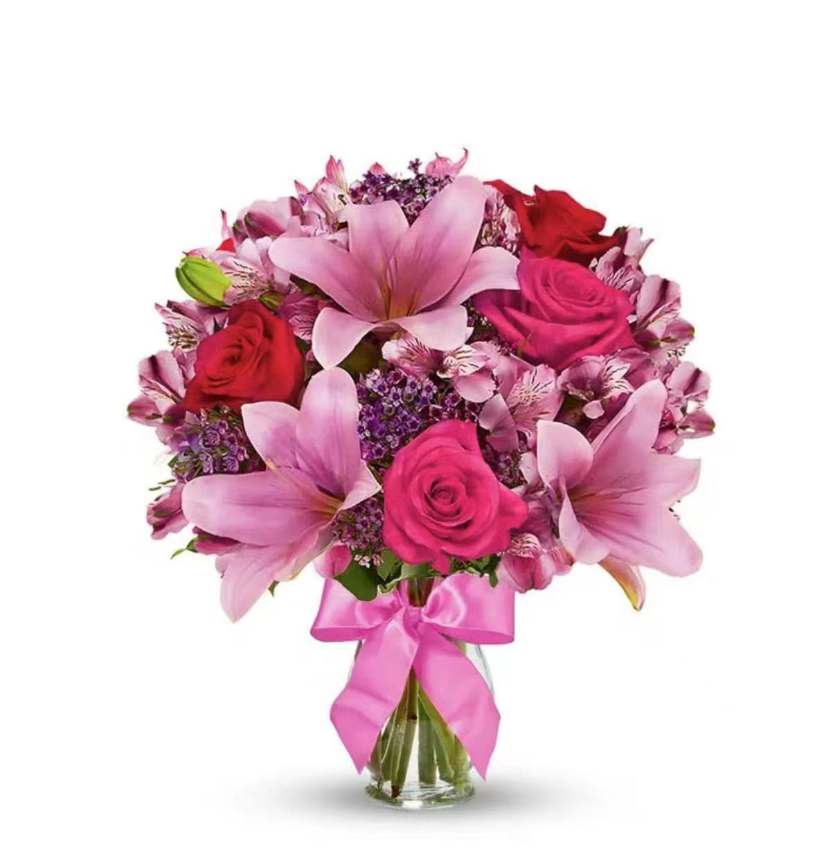 Rose &amp; Lily Celebration - A vibrant and elegant arrangement designed to brighten any occasion. This bouquet features stunning hot pink roses, symbolizing admiration and joy, paired with graceful pink lilies that add a soft, fragrant touch. It also includes delicate wax flowers, charming alstroemeria, and pink robin accents, creating a rich blend of texture and color.  Thoughtfully arranged, this bouquet is perfect for celebrating special moments or simply bringing warmth and beauty to someone’s day.