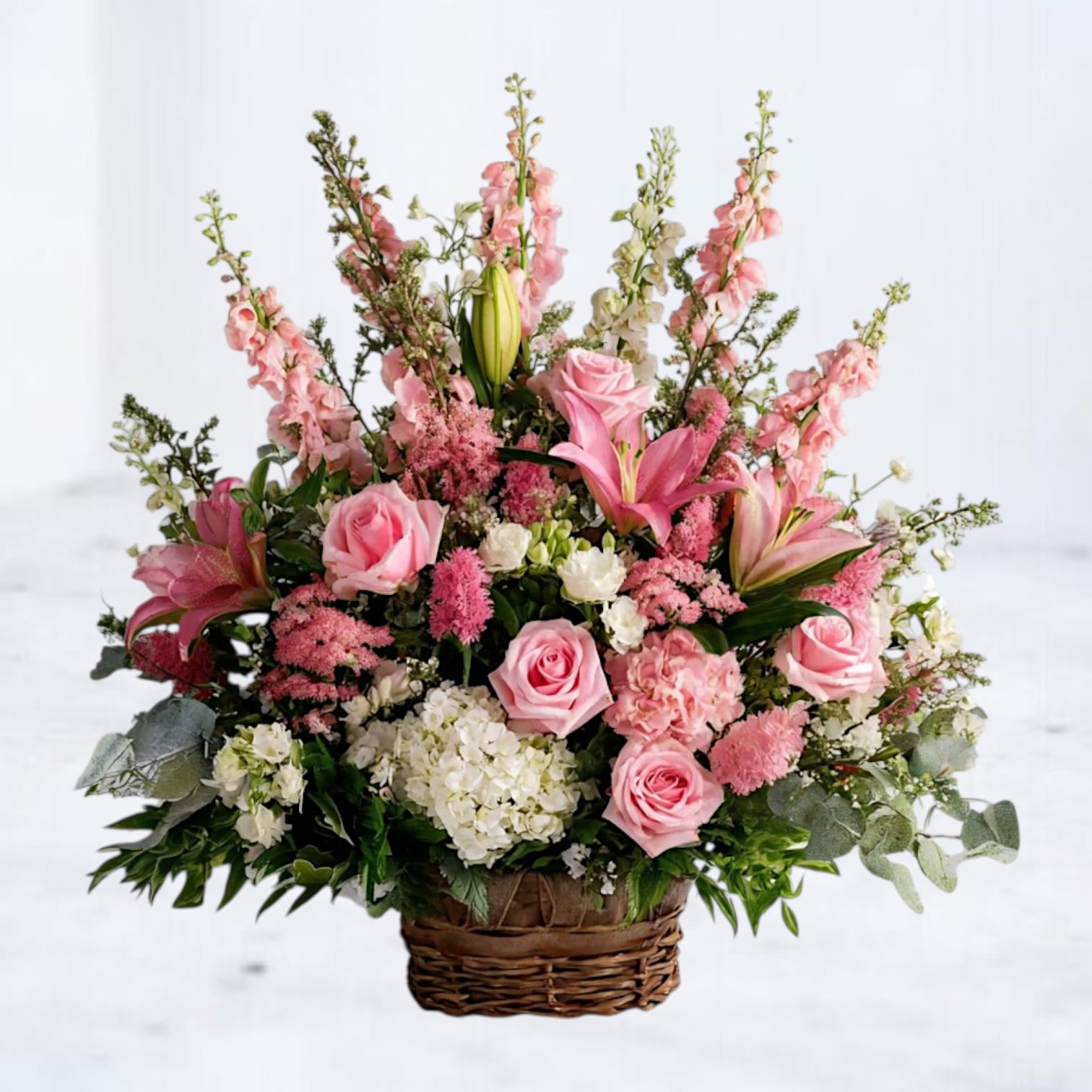 Rose Quartz Tribute Floor Basket - Honor the memory of a loved one with the Rose Quartz Tribute, a graceful sympathy arrangement that conveys heartfelt condolences and love. Featuring delicate pink lilies, hydrangeas, spray roses, and carnations, this piece is beautifully accented with Queen Anne’s lace and lush greenery for a soft, elegant touch. Arranged in a classic vase, this design offers a comforting expression of remembrance and peace.  Perfect for funerals, memorial services, or as a thoughtful gesture for grieving families, the Rose Quartz Tribute is available for same-day flower delivery in Houston and surrounding areas. Let this stunning arrangement serve as a beautiful symbol of compassion and support during difficult times.  Order your sympathy floral arrangement online today to honor a life well-lived and bring comfort to those in mourning.