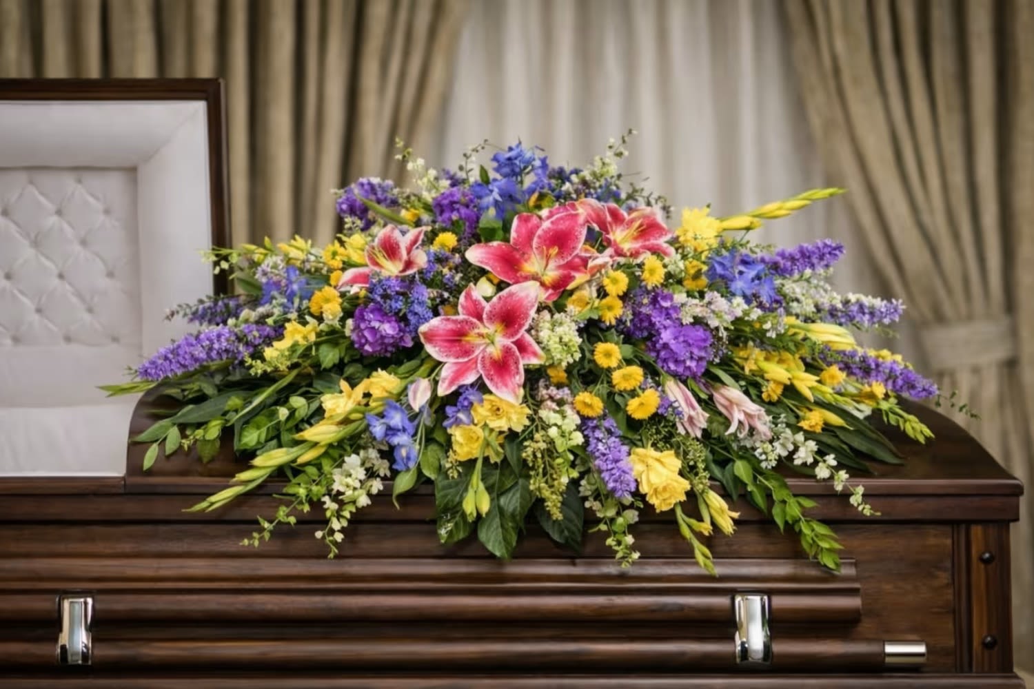 Restful Garden Casket Spray  - The Restful Garden Casket Spray from FloralFabulous is a beautifully balanced and nature-inspired tribute designed to celebrate life with color, warmth, and serenity. This garden-style arrangement features striking pink lilies surrounded by a vibrant mix of yellow blooms, purple flowers, and lush greenery, creating a soft yet expressive cascading design.  The combination of pink, yellow, and purple tones symbolizes love, remembrance, joy, and peace—making this arrangement a meaningful choice for families who wish to honor their loved one with a celebration of life rather than traditional tones. The natural, flowing design reflects the beauty of a garden in bloom, offering comfort and warmth during a difficult time.  Designed to rest gracefully atop the casket, the Restful Garden Casket Spray creates a stunning and uplifting focal point during funeral and memorial services. Its organic style and colorful palette provide a heartfelt expression of sympathy while celebrating a life filled with love and cherished memories.  FloralFabulous proudly provides funeral flower delivery and casket sprays in Round Rock, TX and the greater Austin area, helping families express heartfelt condolences with beauty, care, and compassion.