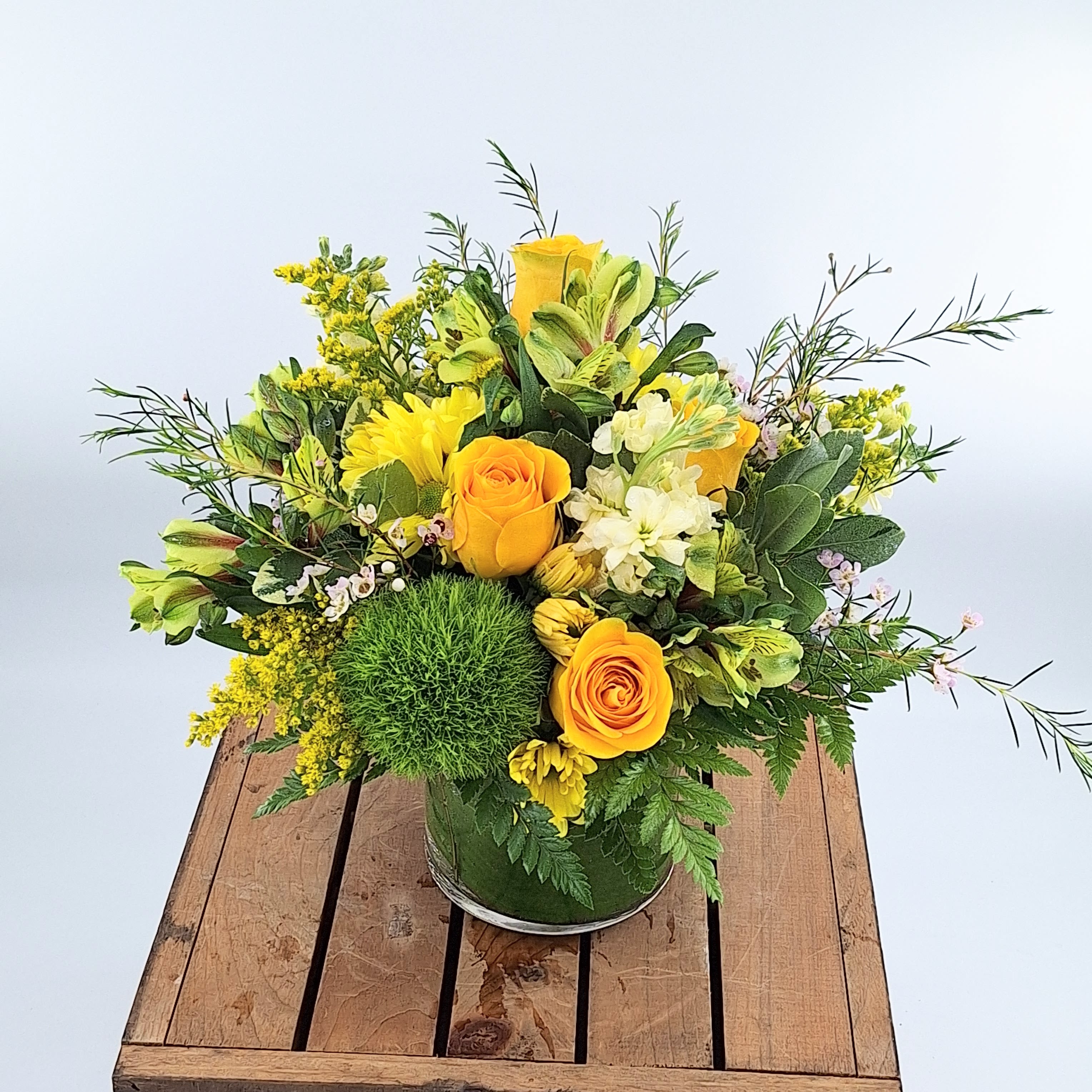 Yellow Optimism (BR) - A Lively Flower Arrangement featuring Solidago, Green Trick Dianthus, Yellow Daisy Poms, Yellow Roses, and Yellow Tulips  This radiant flower arrangement bursts with the lively energy of summer, adorned with a charming medley of yellow blooms and the whimsical touch of green trick dianthus and solidago. Each bloom in this composition is thoughtfully chosen to evoke joy, warmth, and a celebration of life, creating a vibrant display that symbolizes the vibrancy and positivity of the departed spirit.