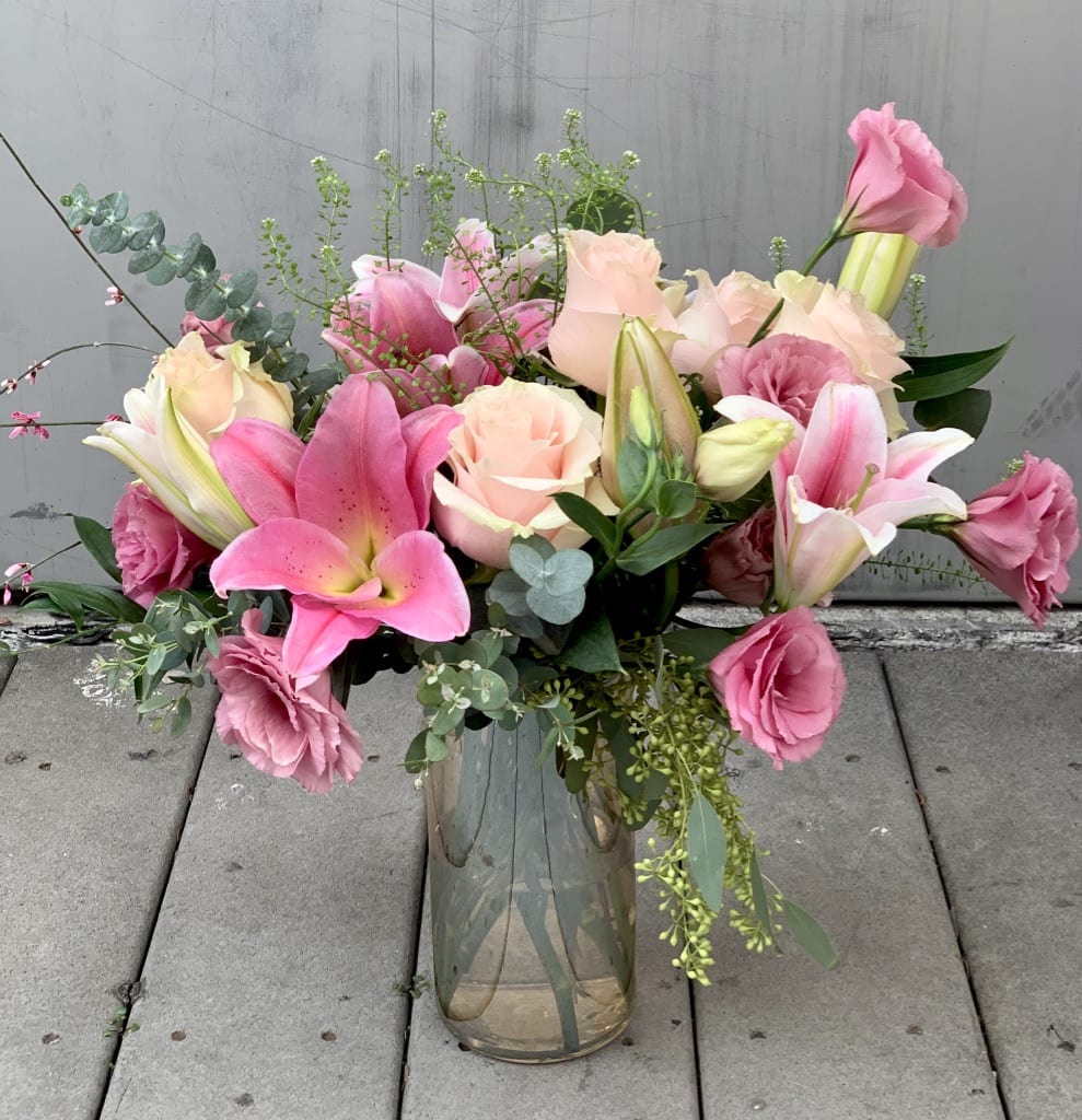Fondly - Pretty lilys, roses and ranunuculus in clear vase.