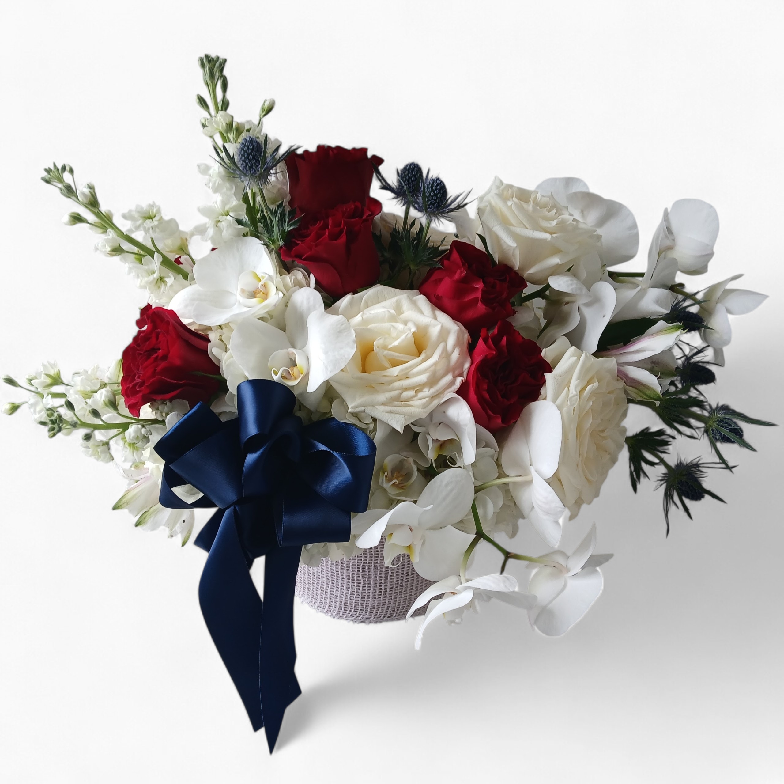 Bouquet of red and white roses with white orchids and a navy ribbon
