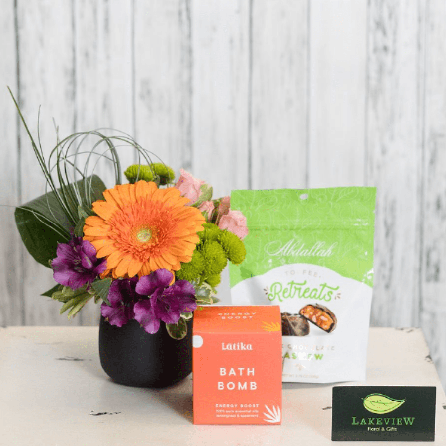 Treat - Treat someone you know to an assortment of goodies including a luxurious a Latika bath bomb, a bag of Abdallah chocolates and a bud vase arrangement consisting of bright blooms like gerbera daisies, alstroemeria and mums.  Approximate Dimensions: 10" T X 10" W  