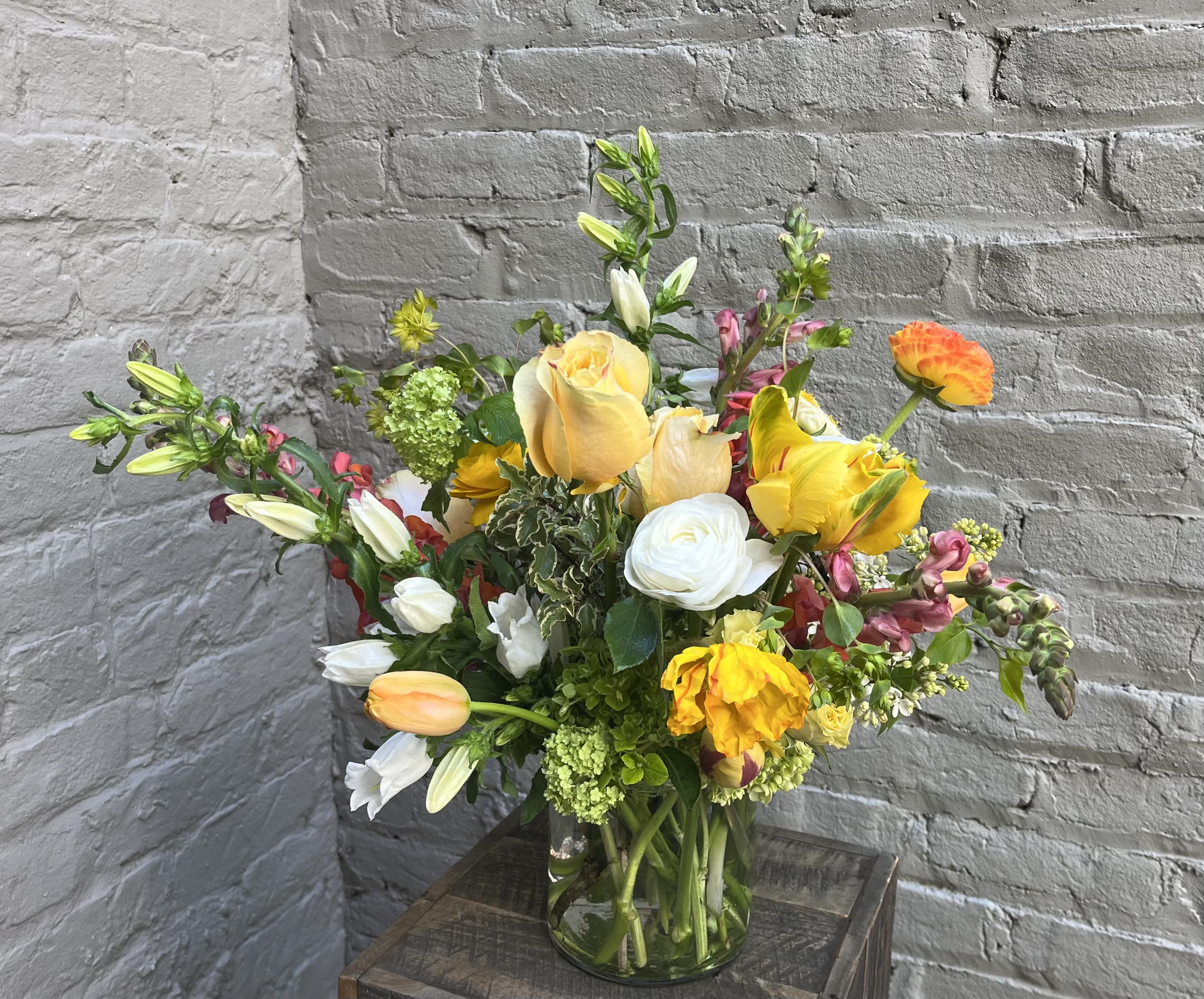 Springtime in Eden - The perfect wild and elegant arrangement to brighten someone's day. This arrangement includes a stunning variety of spring flowers such as campanula, daffodils, tulips, and viburnum.