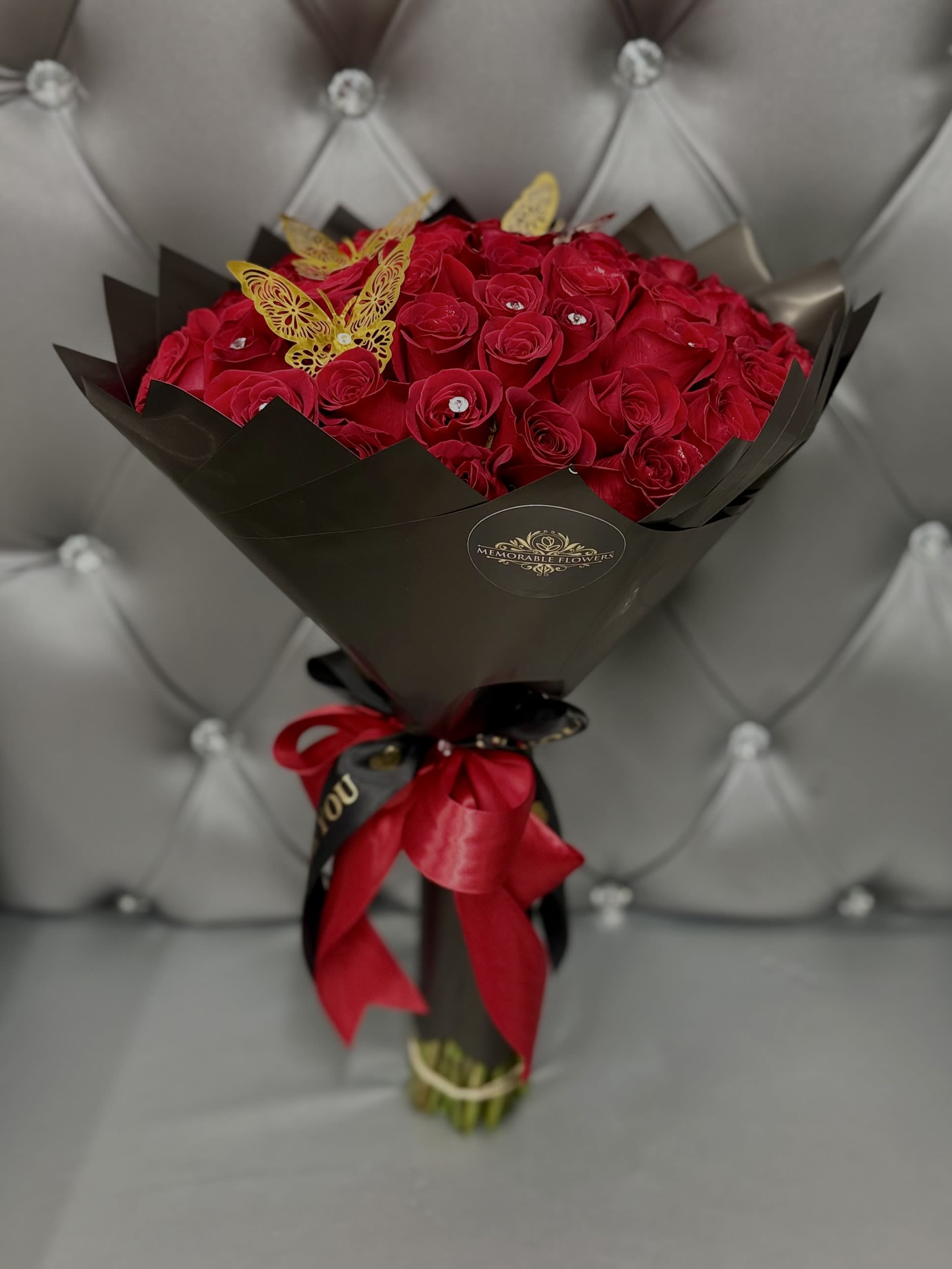 50 RED ROSE BOUQUET - The Rose Bouquet includes 50 long-stem red roses. Wrapped in black paper with a satin red bow. Includes butterflies and diamond pins. 