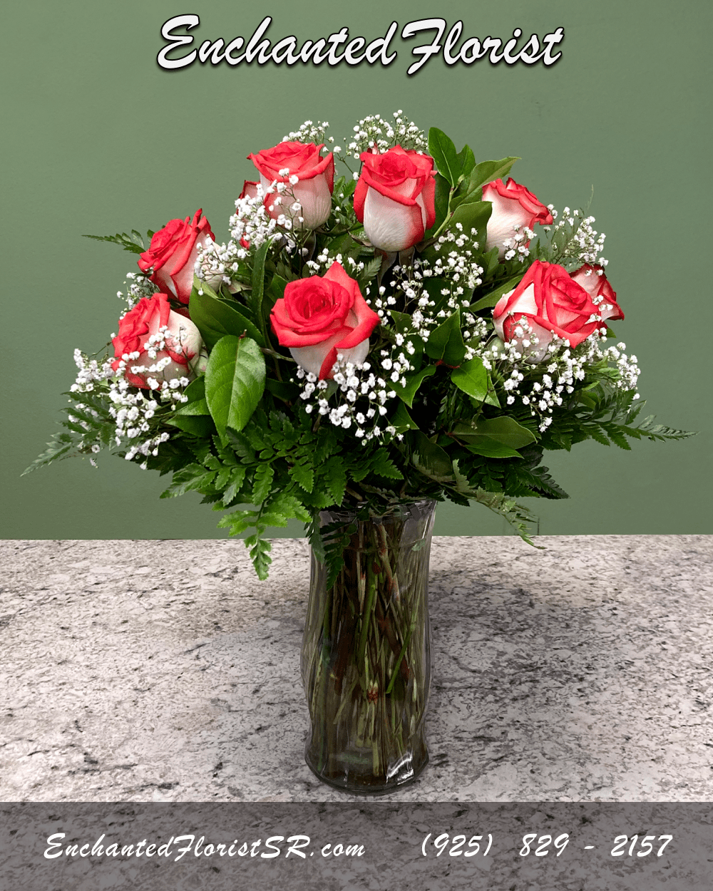 Vase arrangement of red and white roses with baby's breath in a clear glass vase on a stone countertop