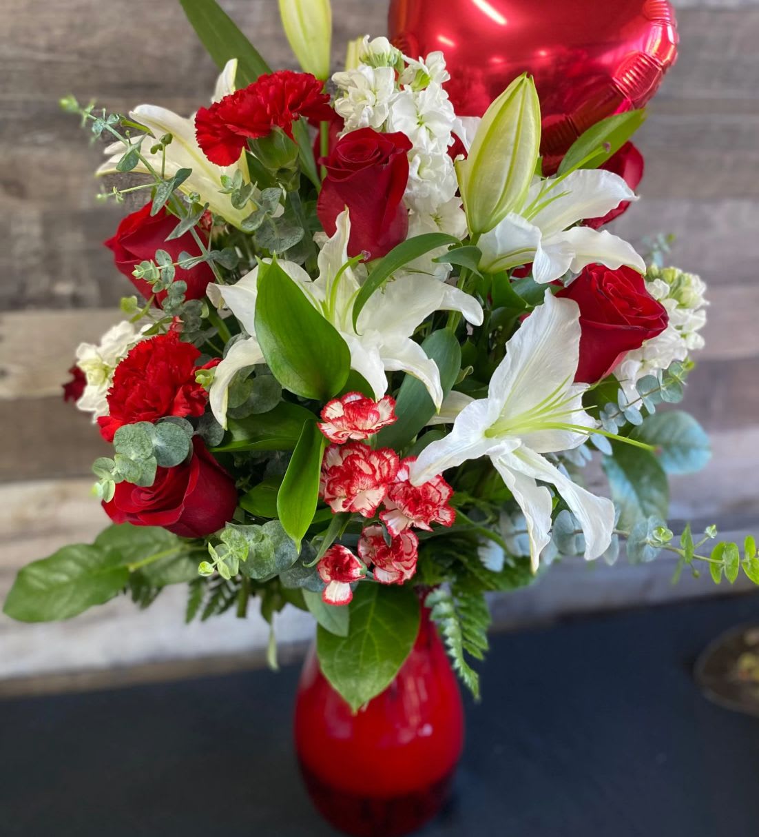 Bouquet of red roses, white lilies, and carnations in a red vase