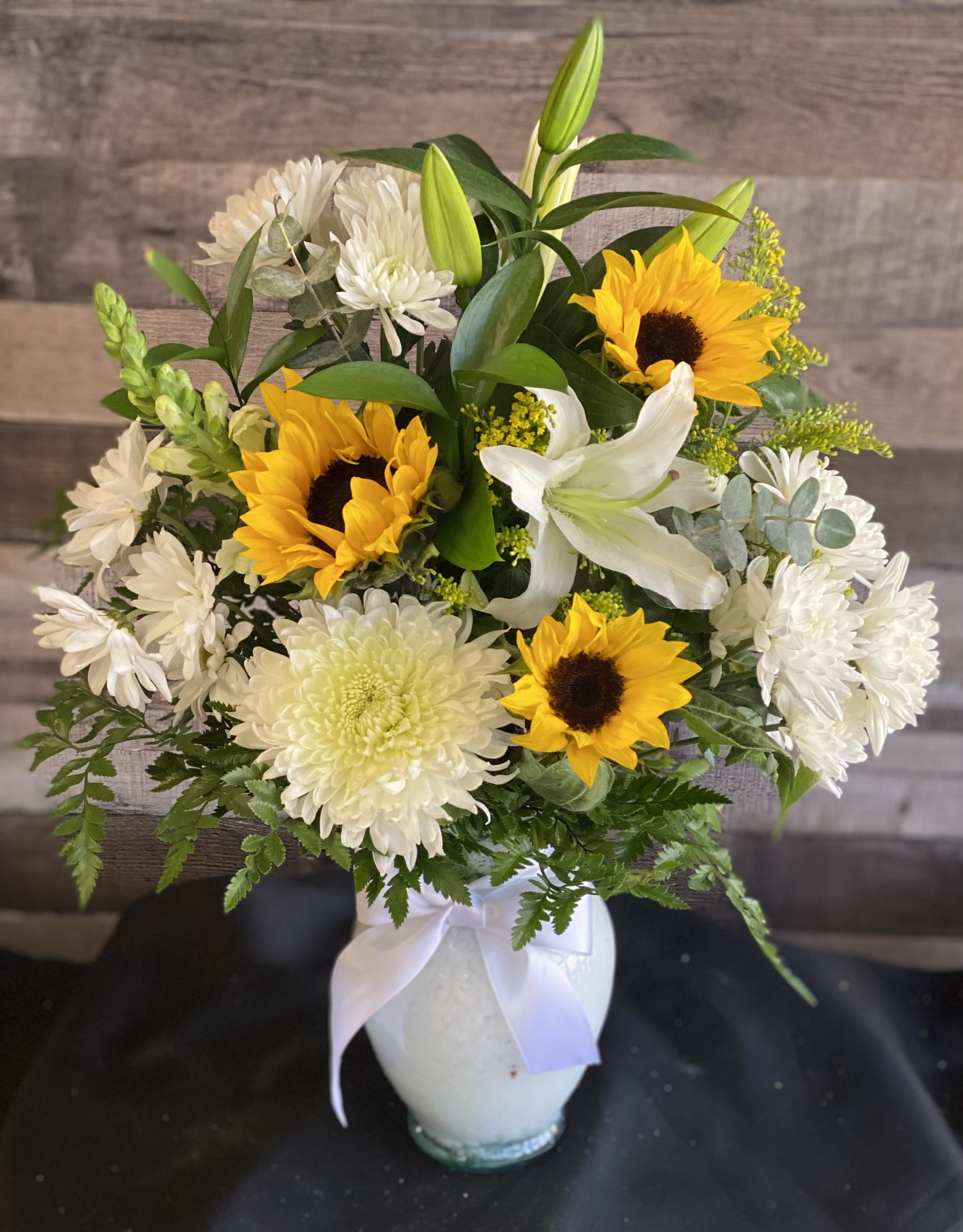 Bouquet of sunflowers, white lilies, and white chrysanthemums in a white vase