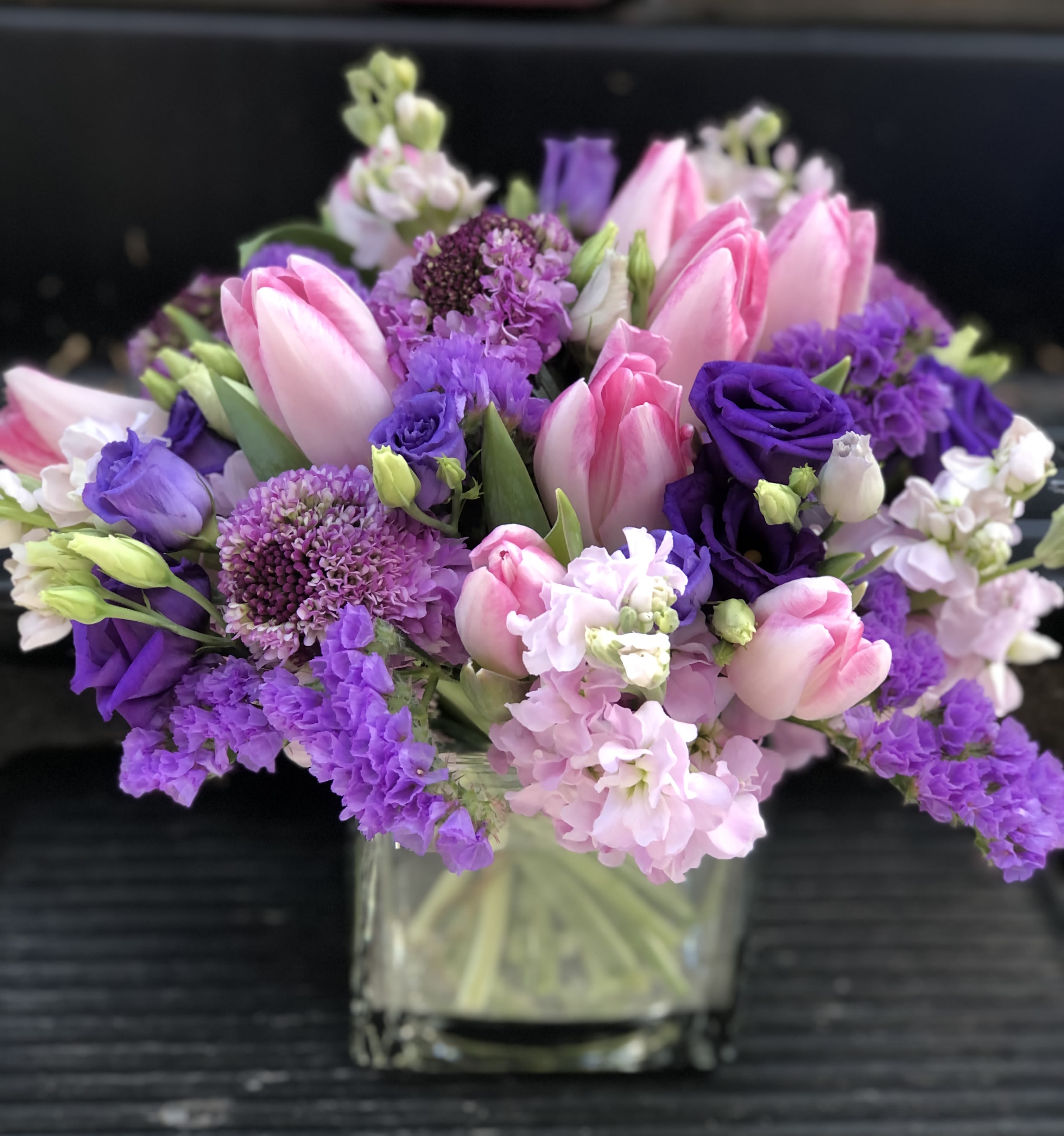 Love Song - The sweetest collection of Purple blossoms and pink tulips among few other interesting elements selected from the freshest inventory available ( may differ from the collection in the picture) presented in designer choice vessel. 