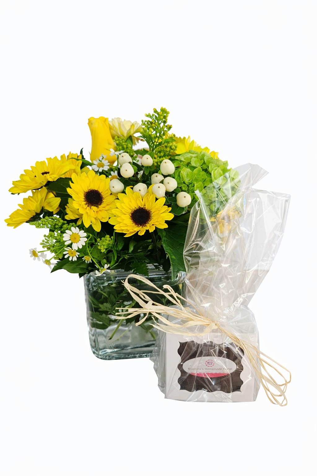 Yellow flower arrangement in a glass cube vase with a wrapped gift box beside it
