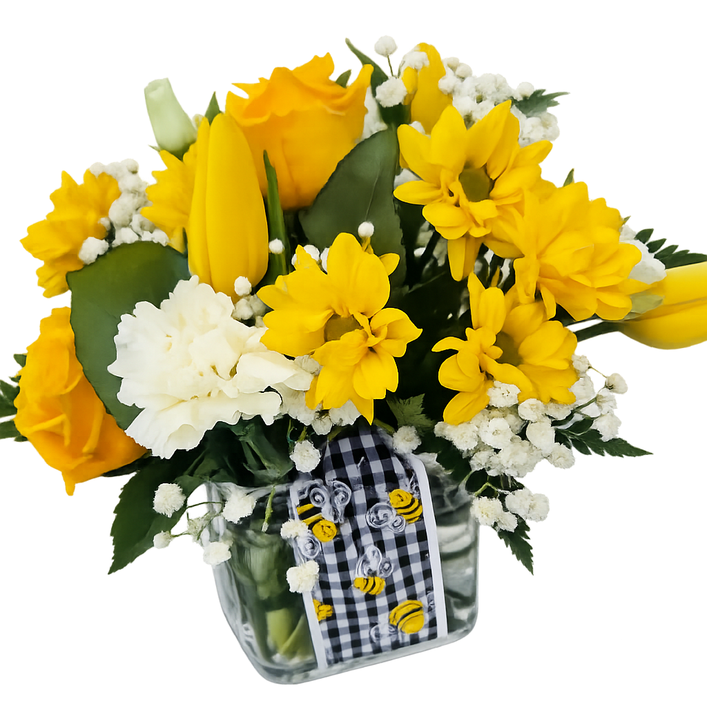 Yellow roses, daisies, and tulips with white carnations in a clear cube vase with a bee ribbon