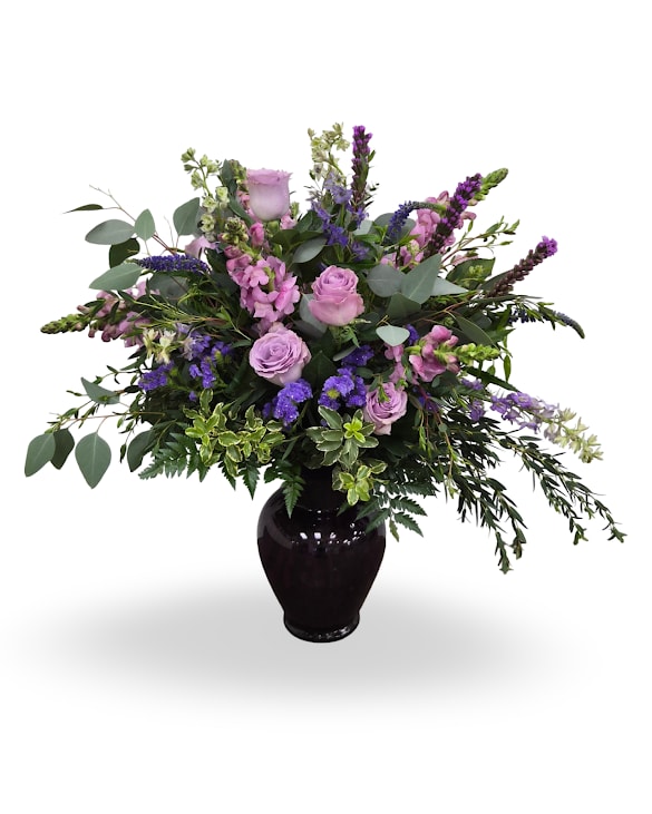Purple Blessing - A graceful mix of lavender roses and rich purple blooms with fresh eucalyptus, arranged in a deep purple keepsake vase. A soft and comforting design full of beauty.  Approximately 27" x 24" x 5"